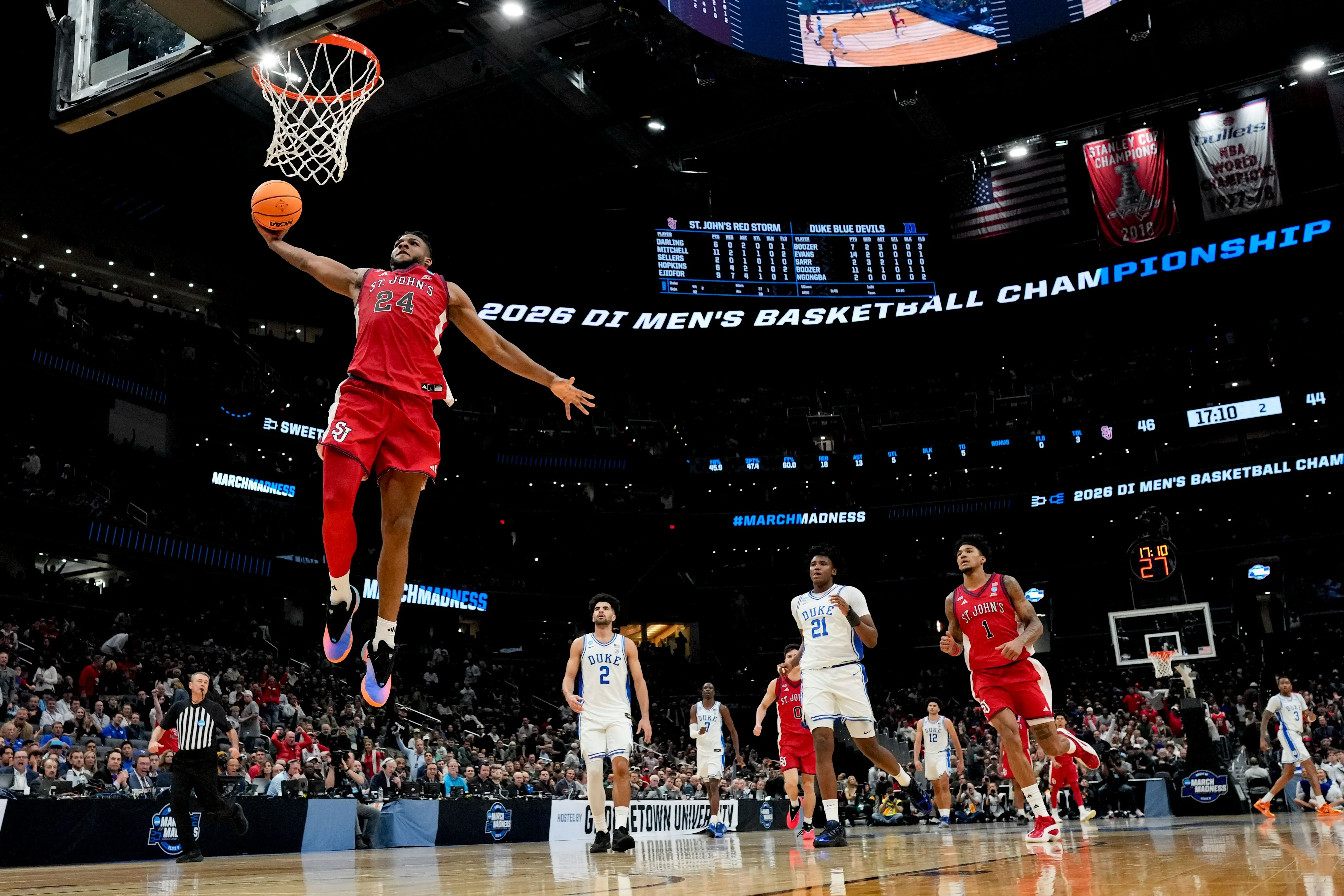 لاعب كرة سلة من فريق سانت جونز يقفز عالياً ليقوم بسلة خلال مباراة ضد ديوك في بطولة NCAA، مع وجود لاعبين آخرين في الخلفية.