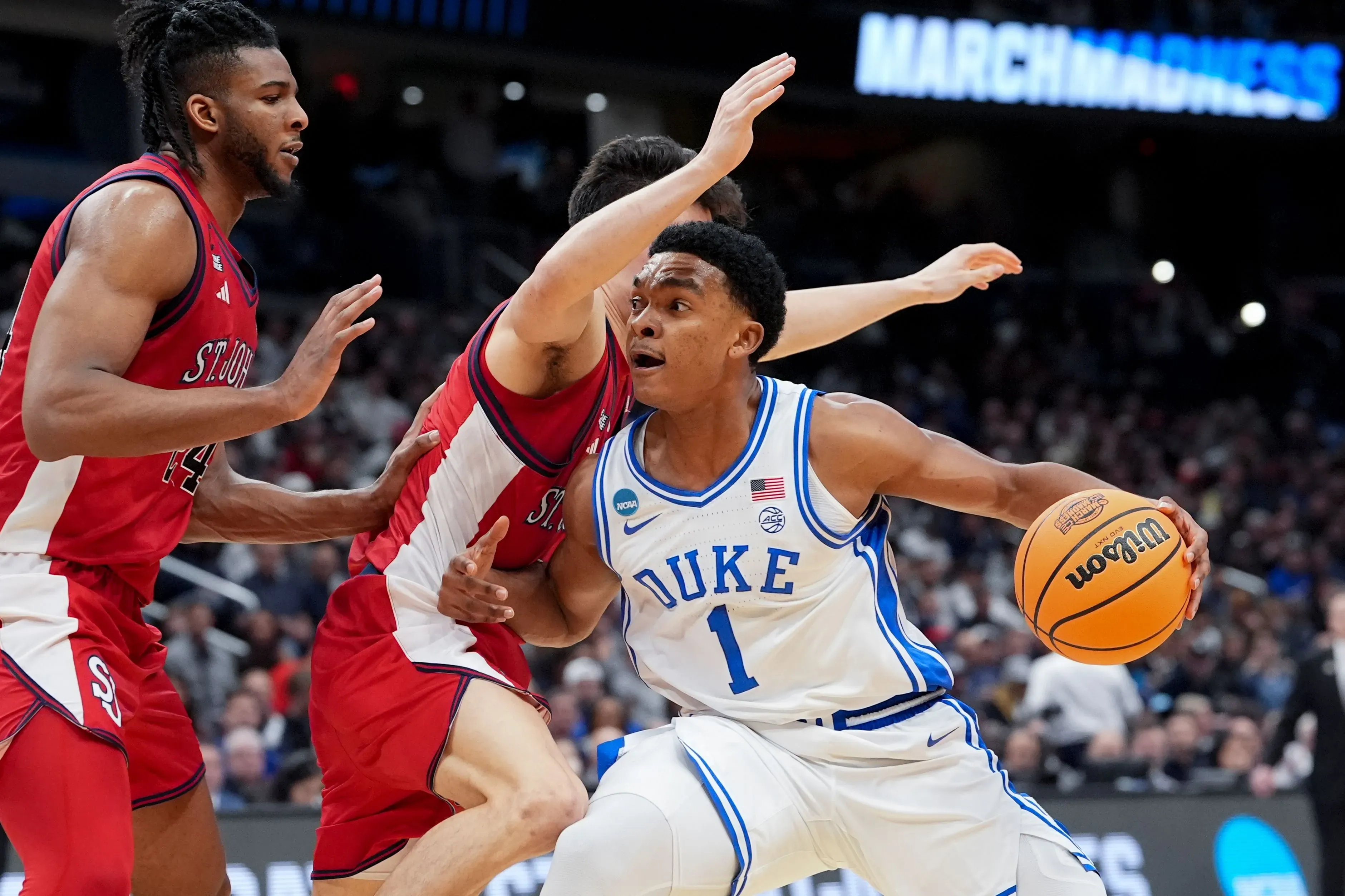 كاليف فوستر، لاعب فريق ديوك، يتجاوز مدافعين من سانت جونز خلال مباراة مثيرة في بطولة مارس مادنس، حيث أظهر إرادة قوية رغم إصابته.