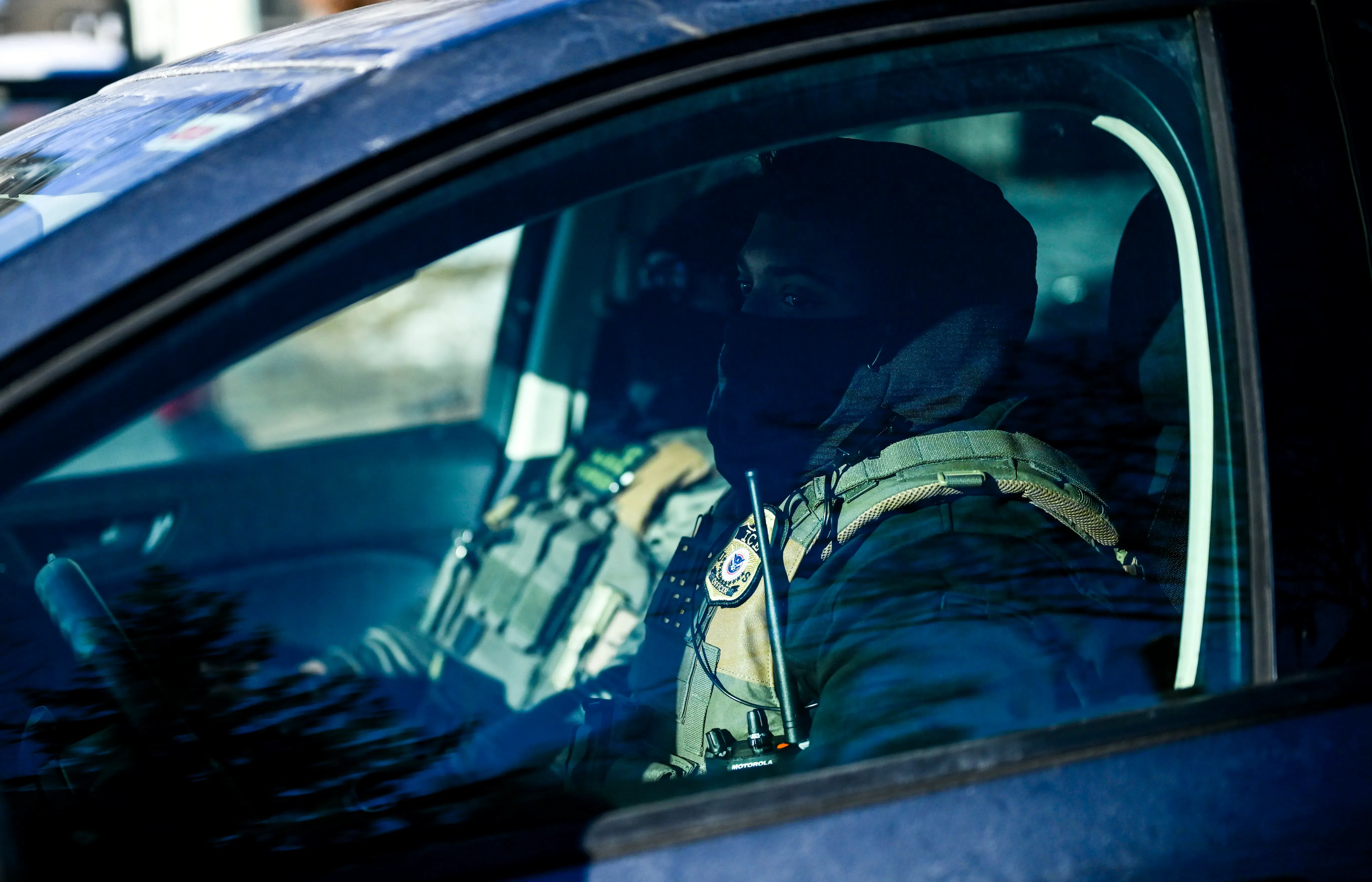 ضباط يرتدون سترات واقية داخل سيارة، يعكسون التوترات الأمنية بعد مقتل المتظاهرين في مينيابوليس.