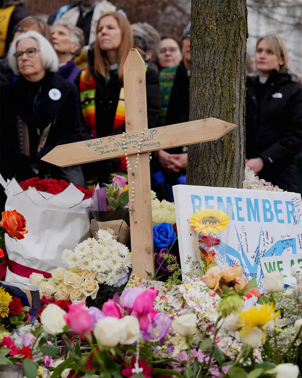 تجمع حشود من المعزين حول نصب تذكاري خشبي مزين بالزهور واللافتات، تخليداً لذكرى رينيه جود وأليكس بريتي بعد مقتلهما.