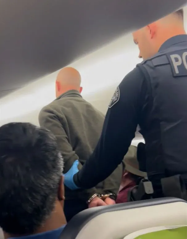 شرطة تطوق رجلاً مكبلاً بالأصفاد داخل طائرة، في سياق تحقيقات حادث تحطم طائرة شحن Miami Air.