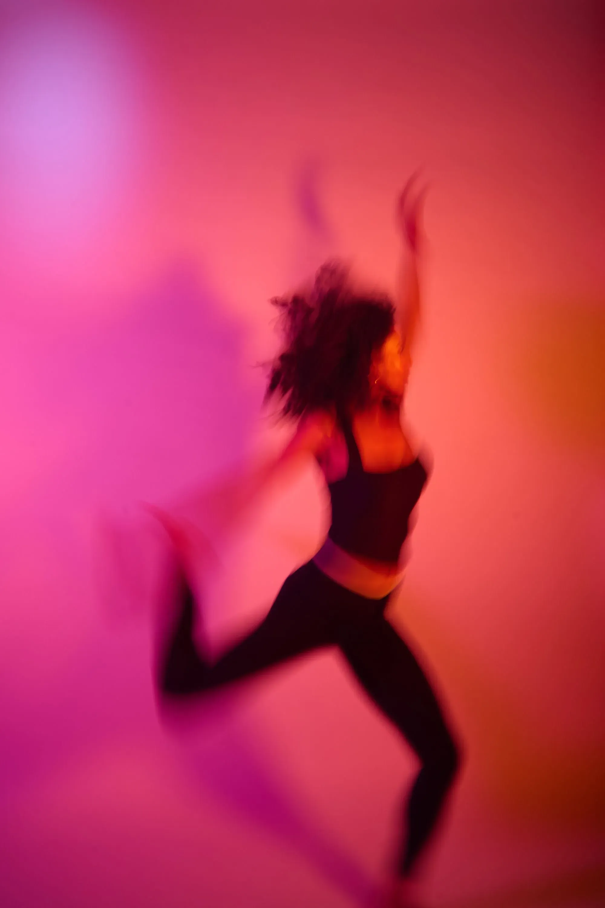 امرأة ترقص بحيوية في إضاءة ملونة، تعكس شعورًا بالحرية والتعبير، مما يعكس موضوع الصحة العقلية والعلاج بالكيتامين.