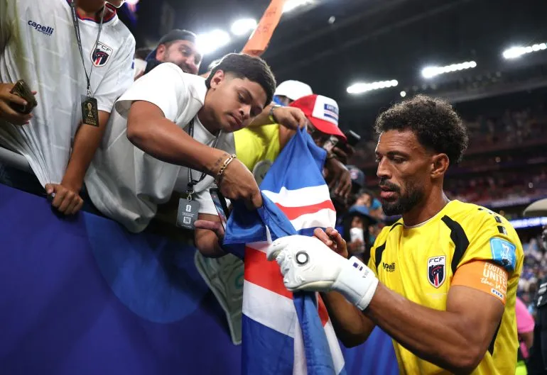 حارس مرمى منتخب الرأس الأخضر يوقع على علم أمام مشجعين خلال كأس العالم 2026، معبرًا عن نجاح المنتخب في البطولة.