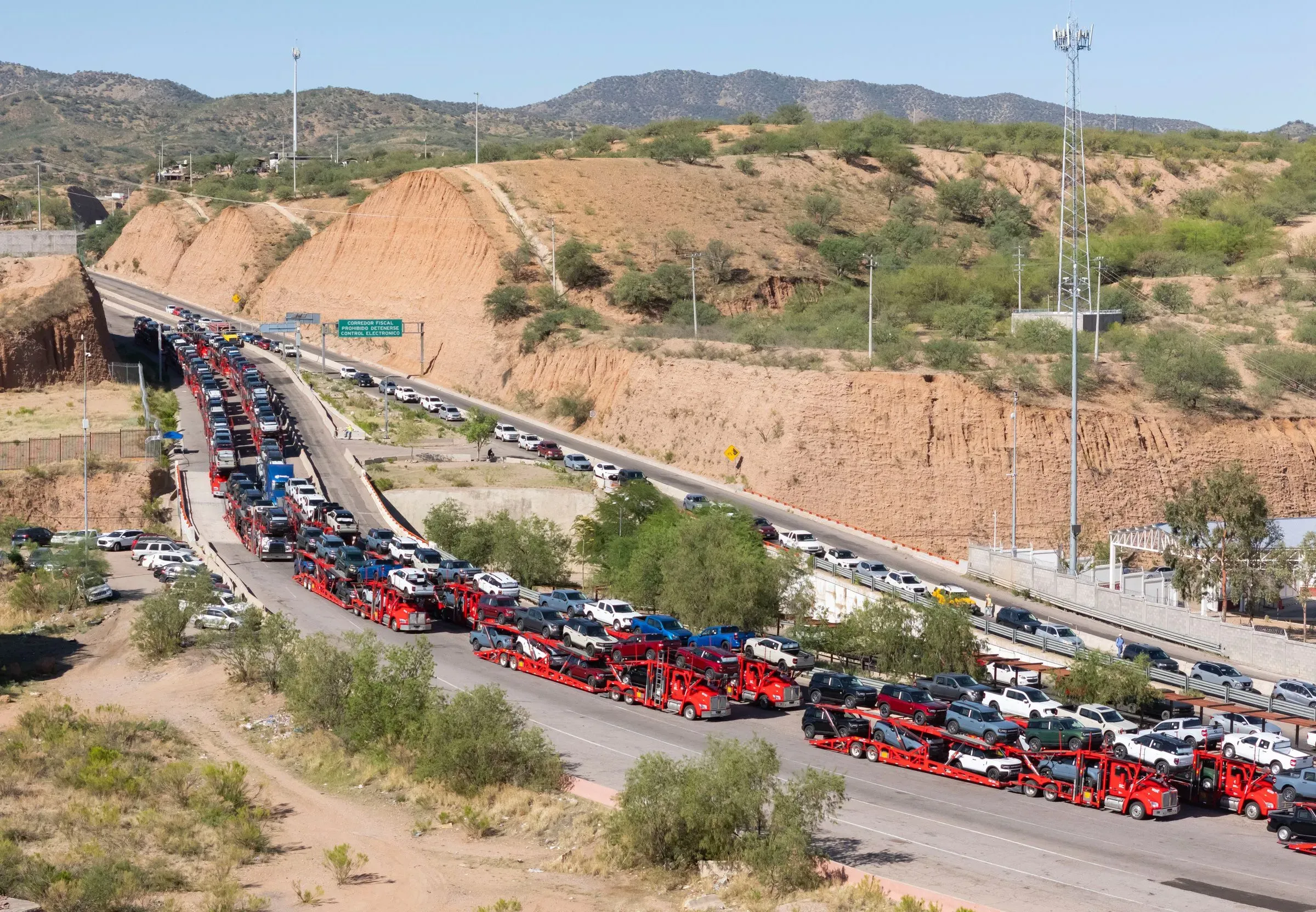 ازدحام مروري على الحدود بين الولايات المتحدة والمكسيك، مع شاحنات تحمل سيارات جديدة، مما يعكس تأثير التعريفات الجمركية على الصناعة.