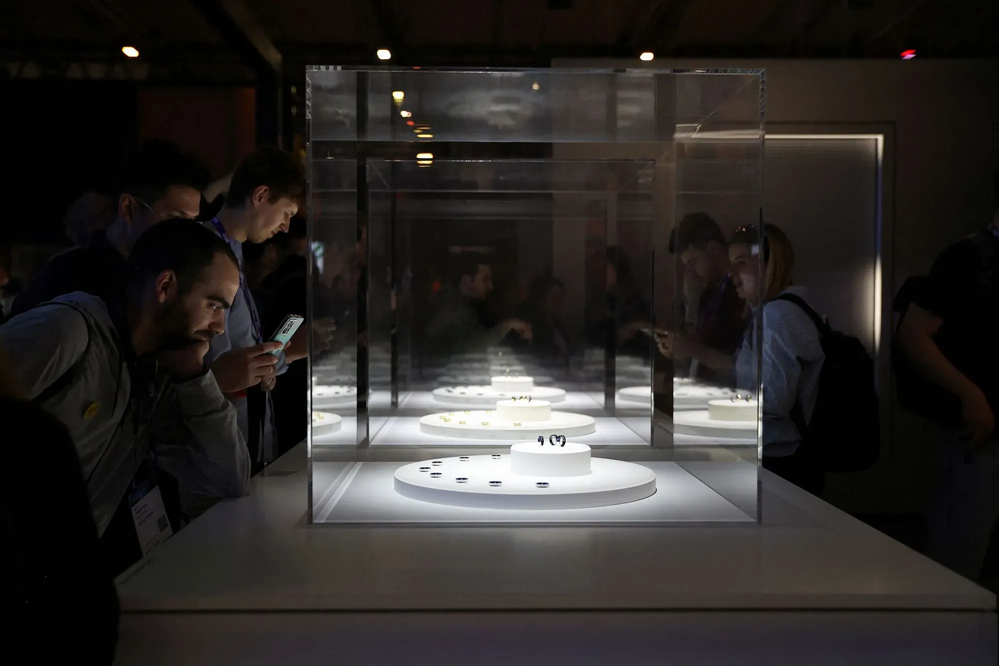 زوار يتفحصون خواتم Oura المعروضة في صندوق زجاجي مضاء، مع التركيز على الابتكار في تكنولوجيا تتبع الصحة.