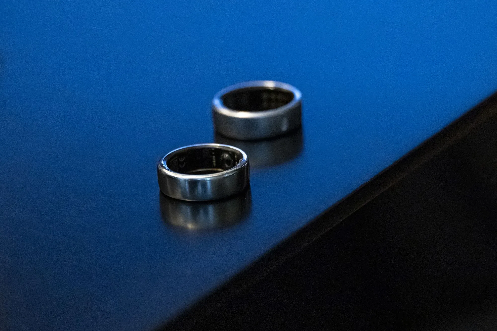 خاتمان معدنيان من Oura على سطح أسود، يمثلان تكنولوجيا تتبع الصحة الحديثة التي تكتسب شعبية بين المستهلكين.