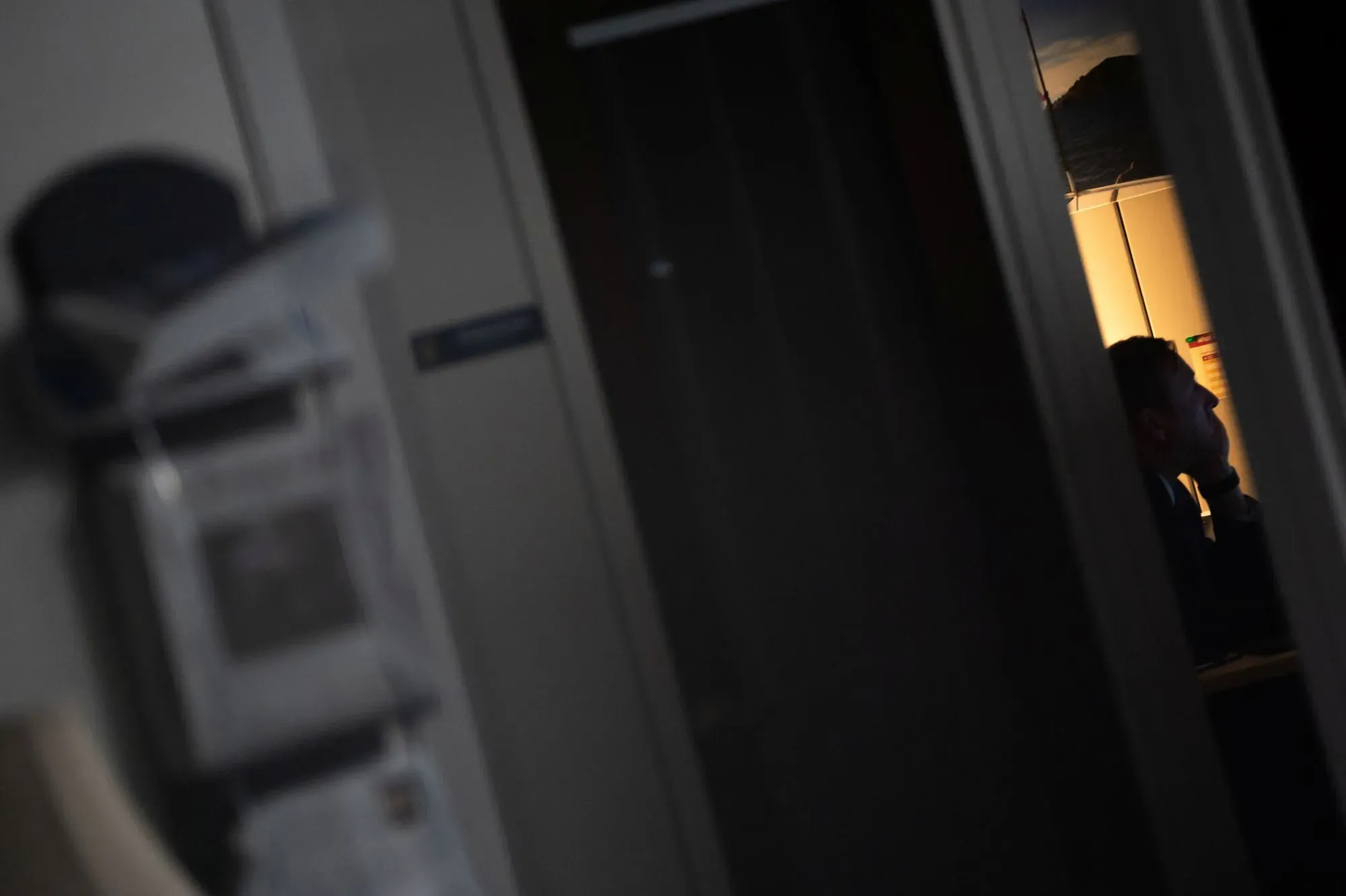 شخص يجلس في غرفة مظلمة، مع إضاءة خافتة خلفه، مما يعكس أجواء التوتر والقلق المرتبطة بالتحقيقات في اتهامات سوء السلوك الجنسي في الكونغرس.