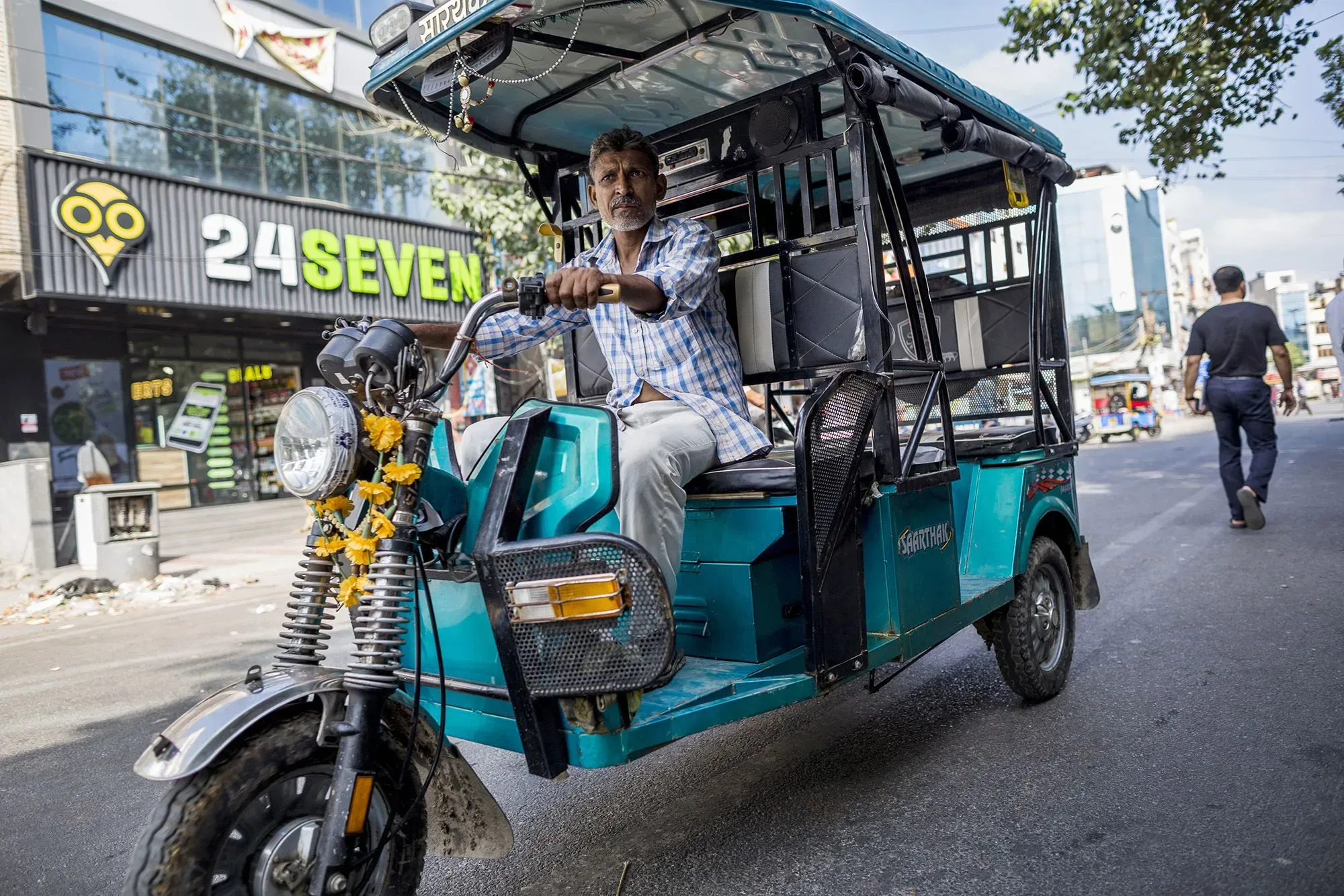 سائق ريكاشة كهربائية في شوارع دلهي، يظهر في الصورة وهو يقود عربة ملونة، تعكس تحول الهند نحو وسائل النقل النظيفة.
