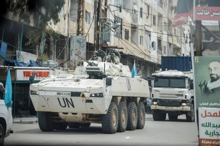 عربة مدرعة تابعة لقوة الأمم المتحدة المؤقتة في لبنان (UNIFIL) تسير في شوارع لبنان، مع جنود على متنها، وسط أجواء من التوتر.