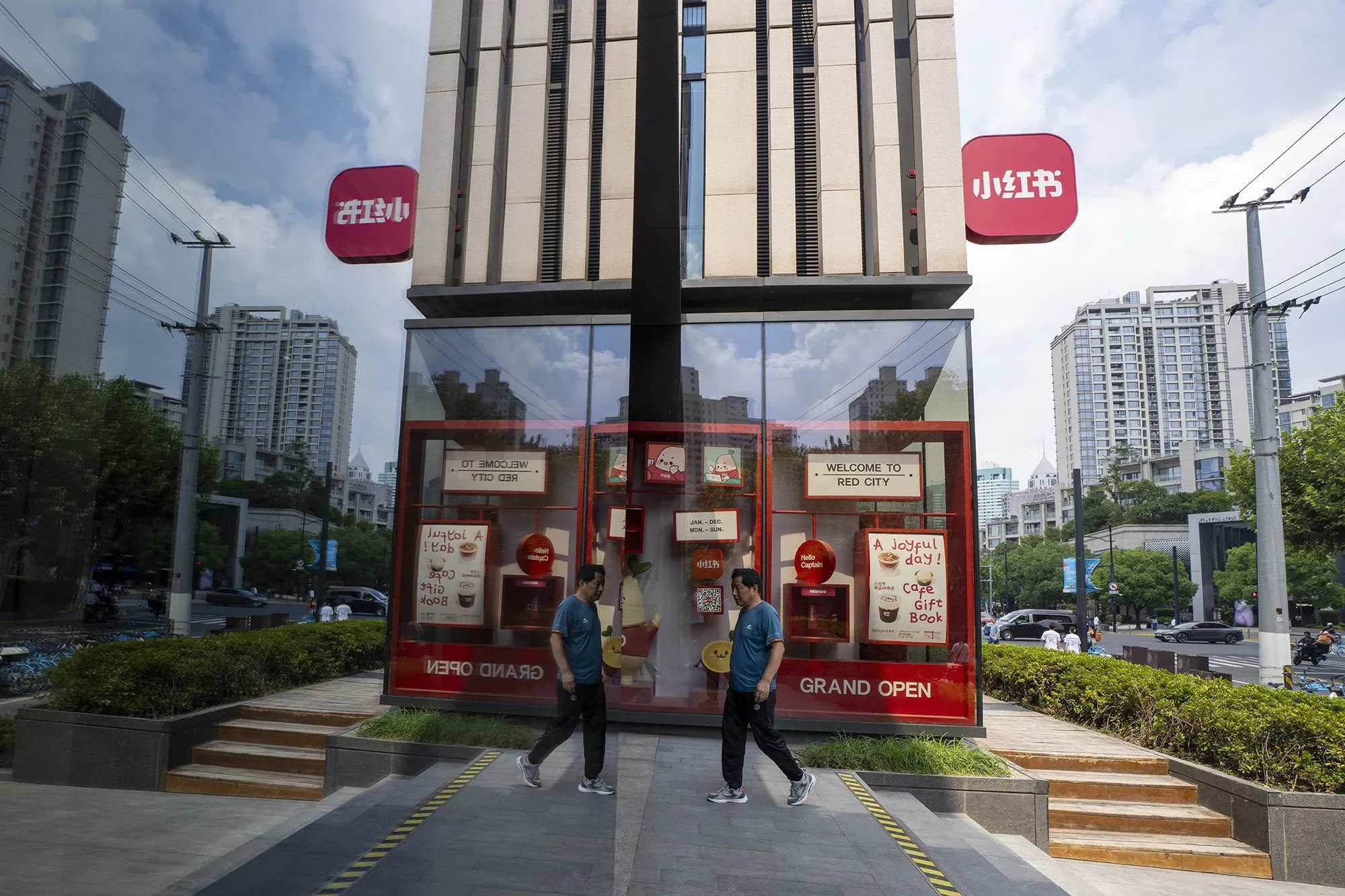 واجهة متجر حديث في مدينة صينية، مع لافتة ترحيبية مكتوب عليها "مرحبًا بكم في مدينة الأحمر"، وشخص يسير بجانب المدخل.