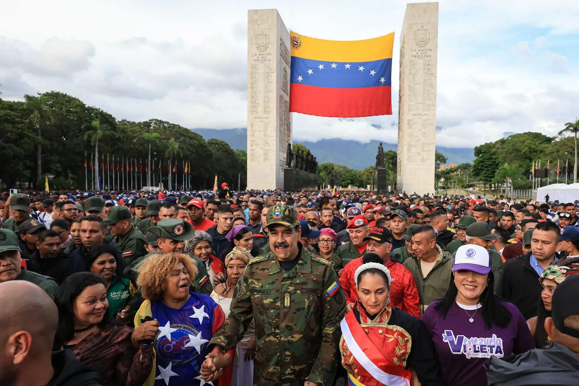 تجمع حاشد في فنزويلا يظهر الرئيس نيكولاس مادورو وسط مؤيديه، مع العلم الفنزويلي يرفرف في الخلفية، مما يعكس التوترات السياسية الحالية.