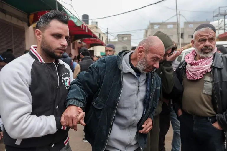 مجموعة من الرجال في شوارع غزة، يظهر أحدهم مسنًا يُساعده شاب، بينما يتجمع آخرون في الخلفية وسط أجواء من التوتر بعد الاشتباكات.