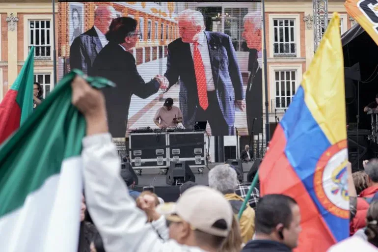 صورة تظهر الرئيس الكولومبي غوستافو بيترو وهو يصافح الرئيس الأمريكي دونالد ترامب، مع أعلام كولومبيا والمكسيك في الخلفية.