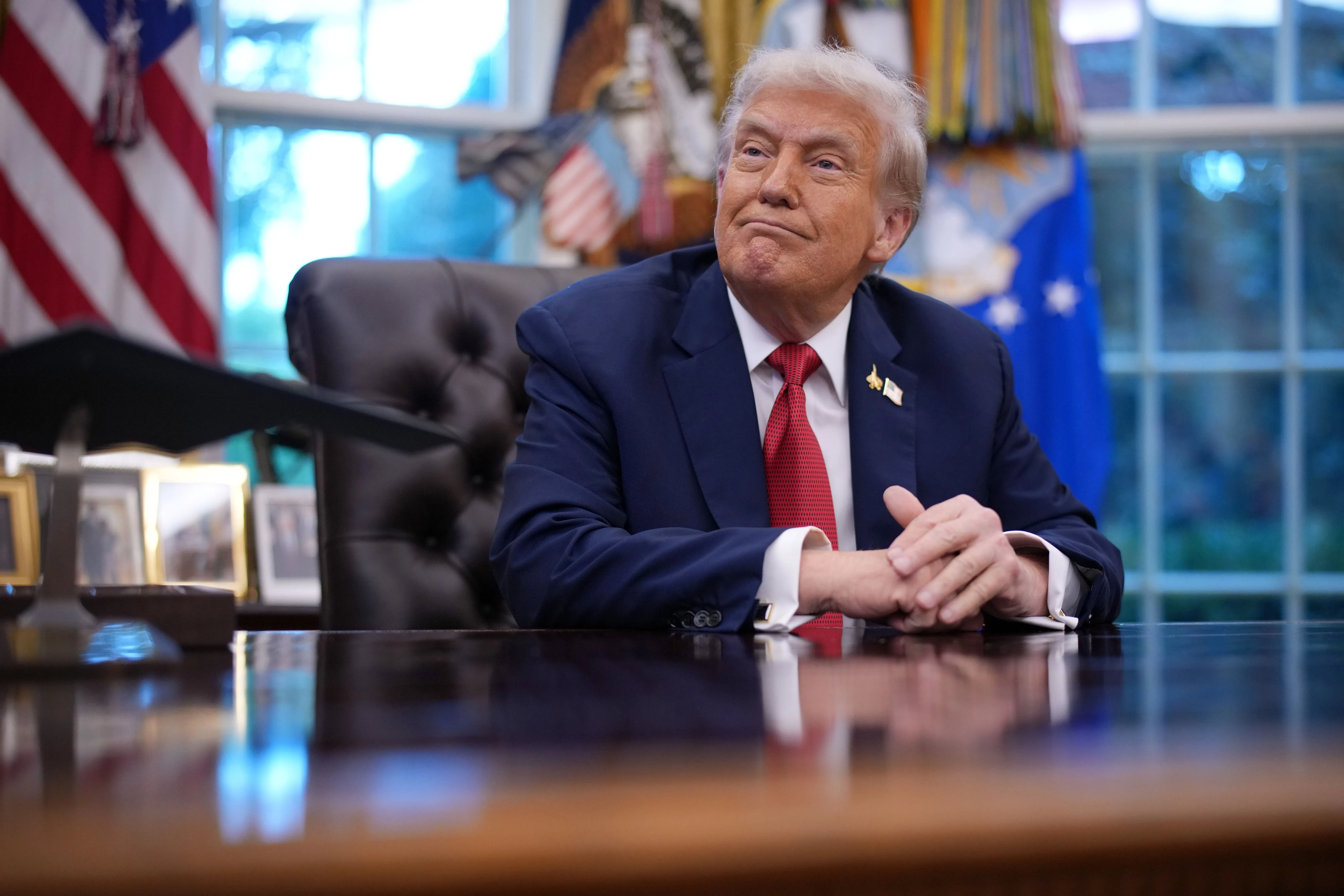 ترامب يجلس في المكتب البيضاوي، مبتسمًا، مع العلم الأمريكي خلفه، في سياق حديثه عن استهداف خصومه السياسيين.