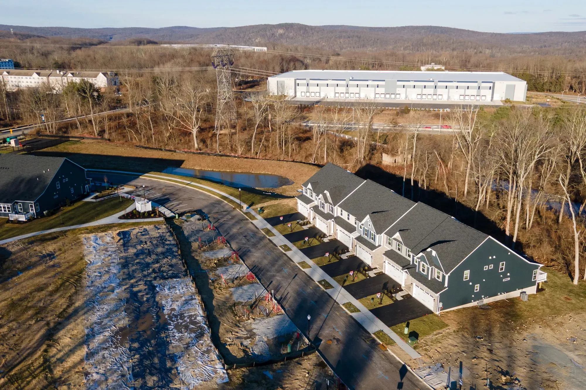 مشهد يظهر مجموعة من المنازل الحديثة في حي سكني، مع وجود مبنى صناعي في الخلفية، يعكس جهود الكونغرس لمعالجة أزمة الإسكان.