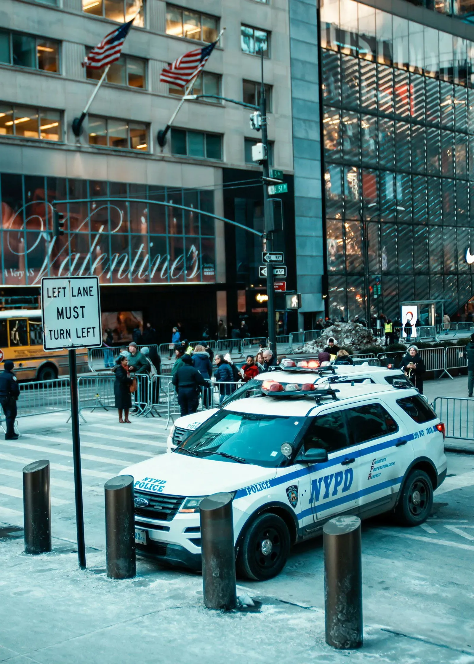 سيارة شرطة تابعة لشرطة نيويورك (NYPD) متوقفة في الشارع، مع وجود حشود من الناس ولافتات توجيهية، تعكس التوترات حول إنفاذ قوانين الهجرة.