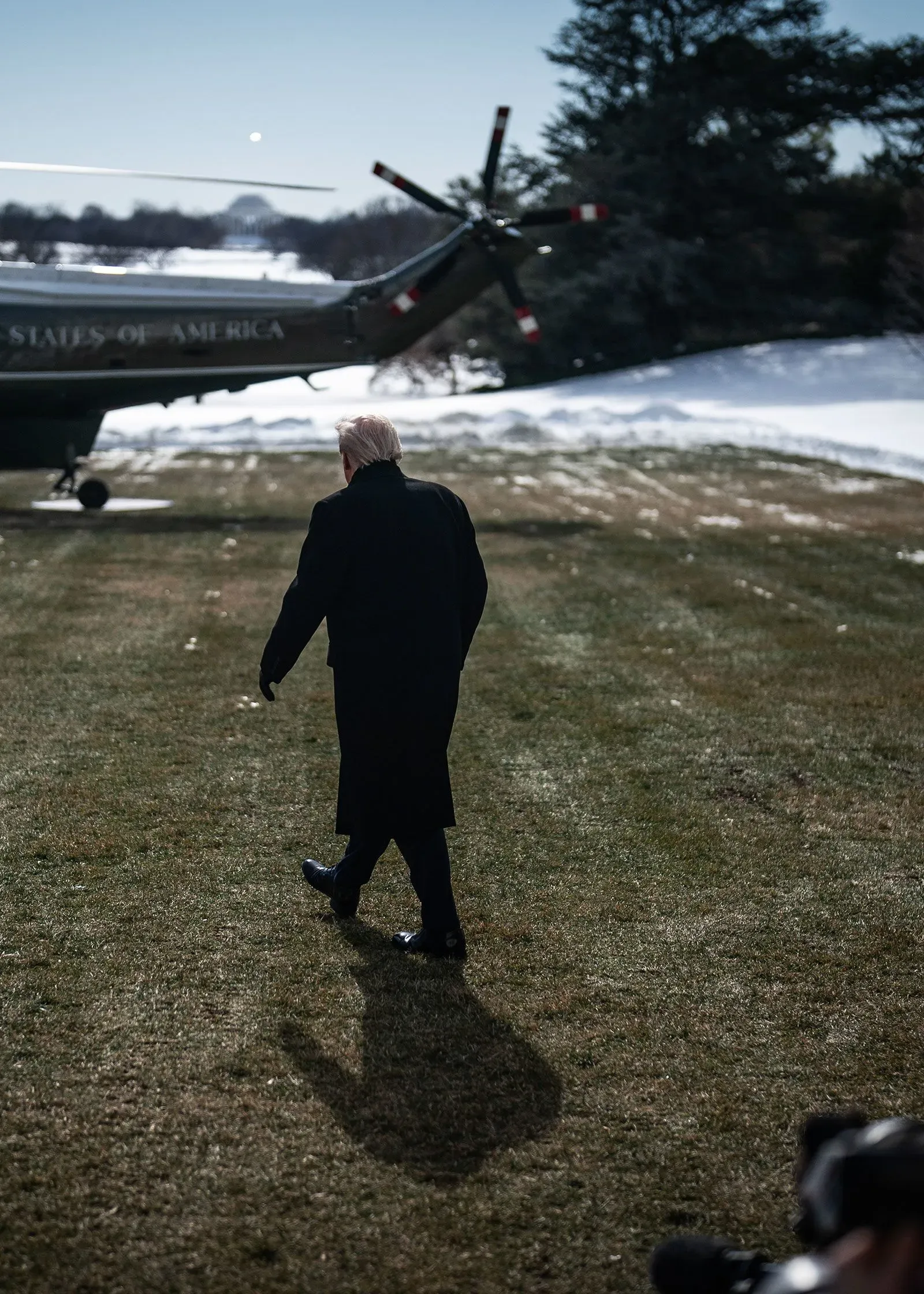 رجل يسير نحو مروحية في منطقة مغطاة بالثلوج، مما يعكس التوترات بين سياسات الهجرة الفيدرالية والسلطات المحلية.