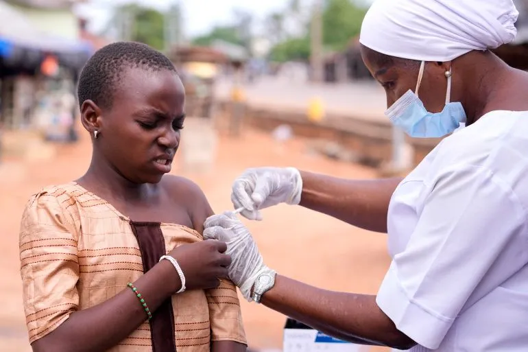 فتاة صغيرة تتلقى لقاح فيروس الورم الحليمي البشري (HPV) من ممرضة في موقع تطعيم، مما يعكس جهود الوقاية من سرطان عنق الرحم.