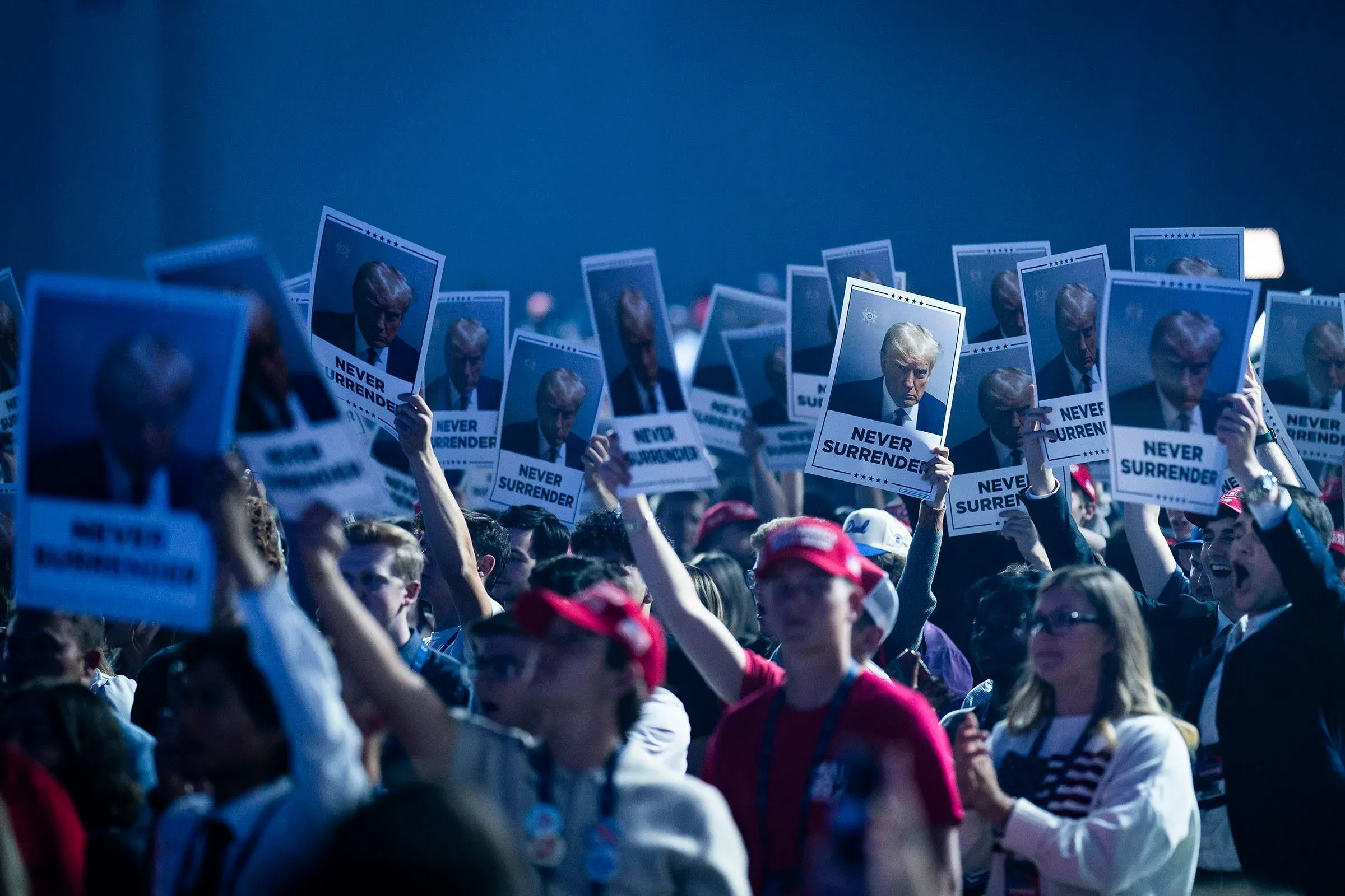 حشد من المؤيدين يحملون لافتات تحمل صورة ترامب وكلمات "لا تستسلموا"، في تجمع سياسي يعكس دعمهم القوي له.