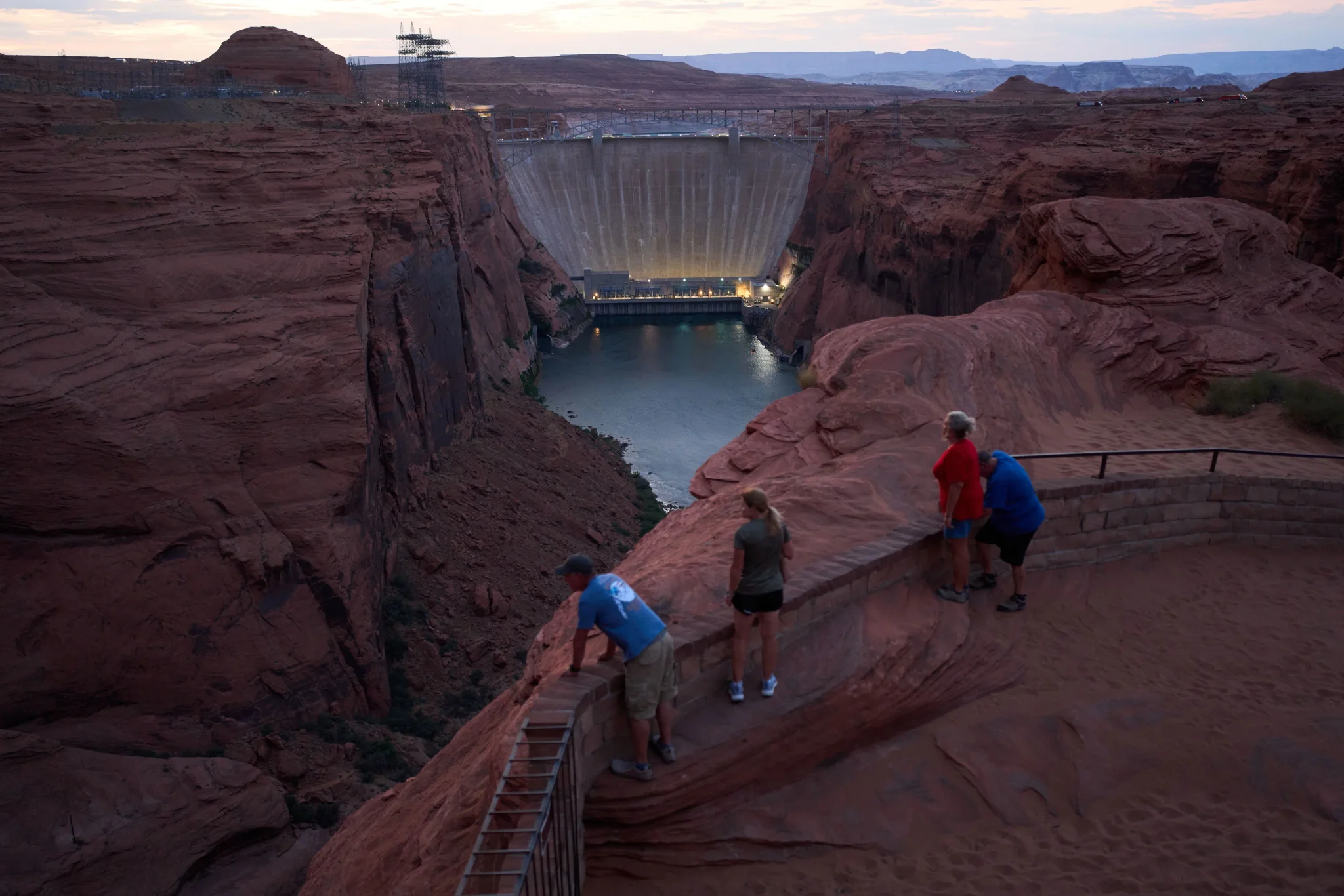 سد Glen Canyon الضخم بين منحدرات صخرية حمراء مع زوار يشاهدون انخفاض منسوب المياه في بحيرة Powell، في ظل أزمة نهر Colorado وتراجع مخزون المياه.