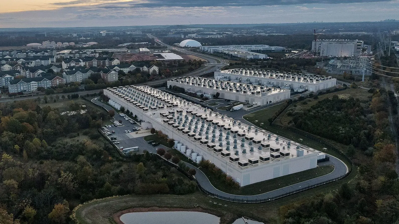 صورة جوية لمراكز بيانات كبيرة في شمال فيرجينيا، تُظهر المباني الحديثة وأنظمة التبريد، تعكس زيادة استهلاك الطاقة وتأثيرها على فواتير الكهرباء.