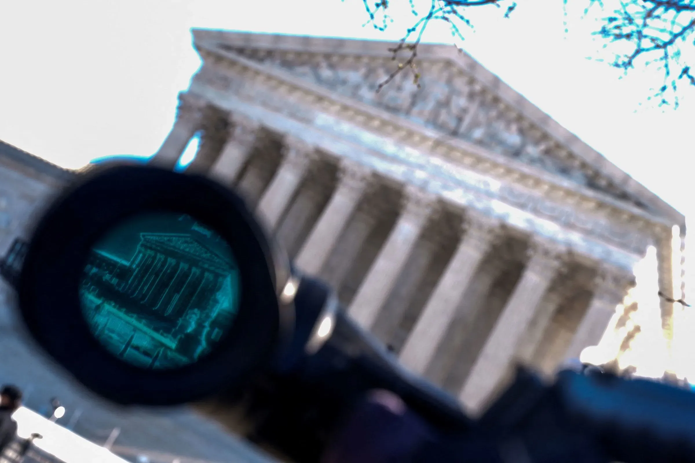 صورة تُظهر مبنى المحكمة العليا الأمريكية من خلال منظار، مما يرمز إلى التوترات السياسية والانتخابات النصفية المقبلة.