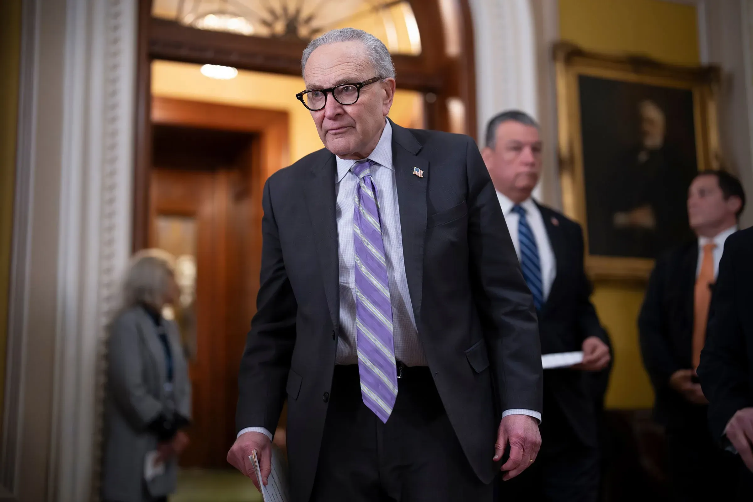 سيناتور تشاك شومر يدخل قاعة مجلس الشيوخ، محاطًا بمساعدين، في سياق مناقشات حول الانتخابات النصفية وقوانين التصويت.