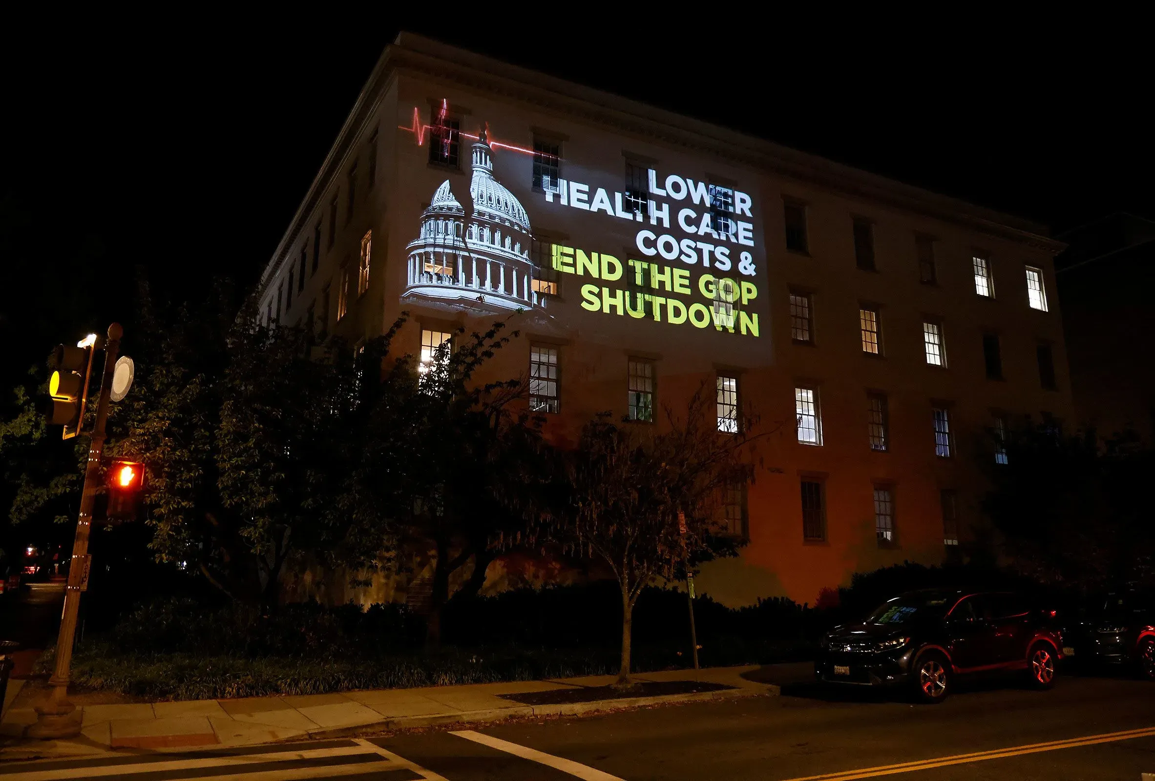 إضاءة على جدار مبنى تعرض شعارات تطالب بخفض تكاليف الرعاية الصحية وإنهاء الإغلاق الحكومي الذي تسببت فيه الجمهوريون.