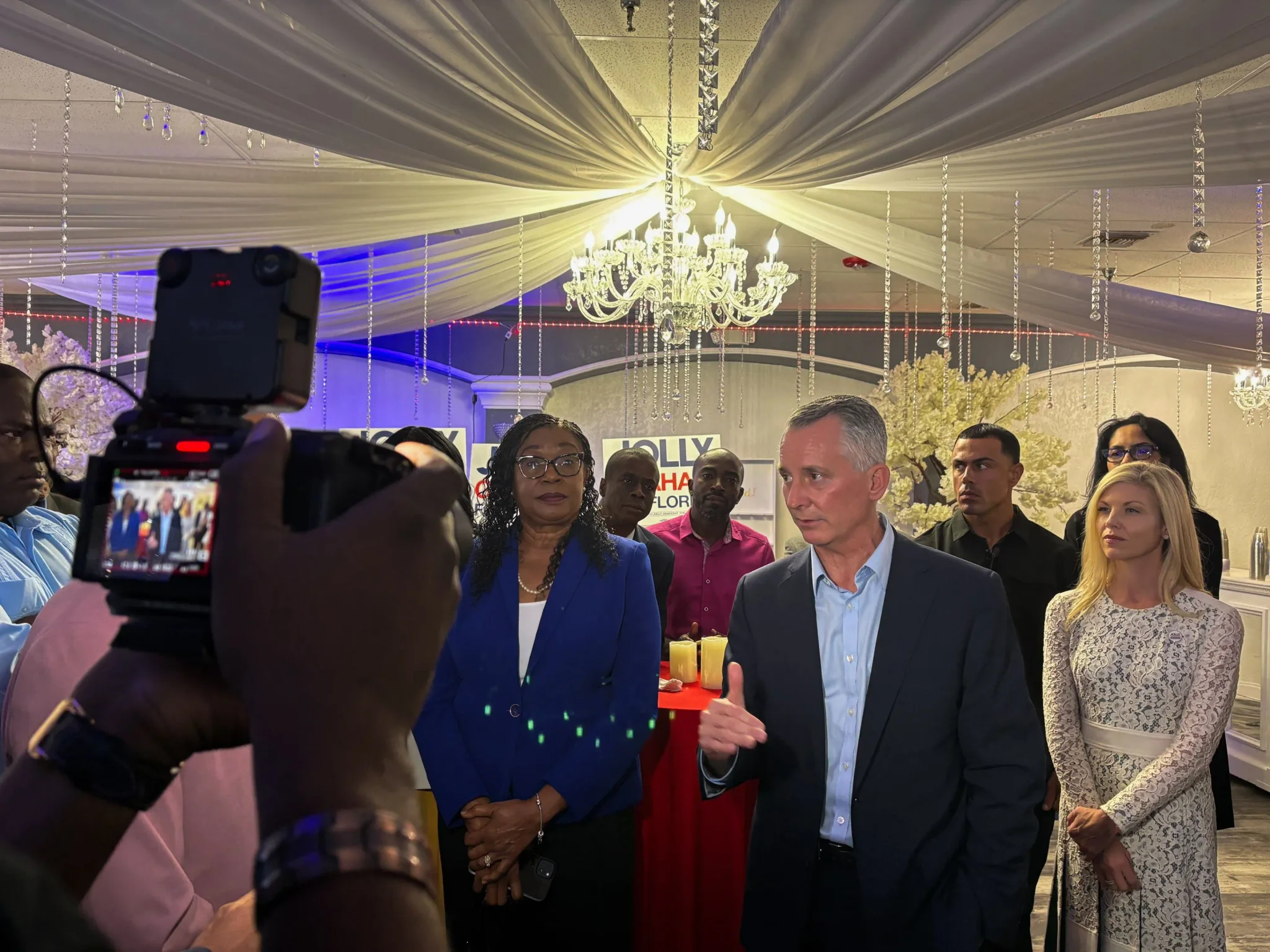ديفيد جولي يتحدث أمام مجموعة من مؤيديه في لقاء انتخابي بنورث لودرديل بفلوريدا وسط تغطية إعلامية، ضمن حملة انتخابية تنافسية.