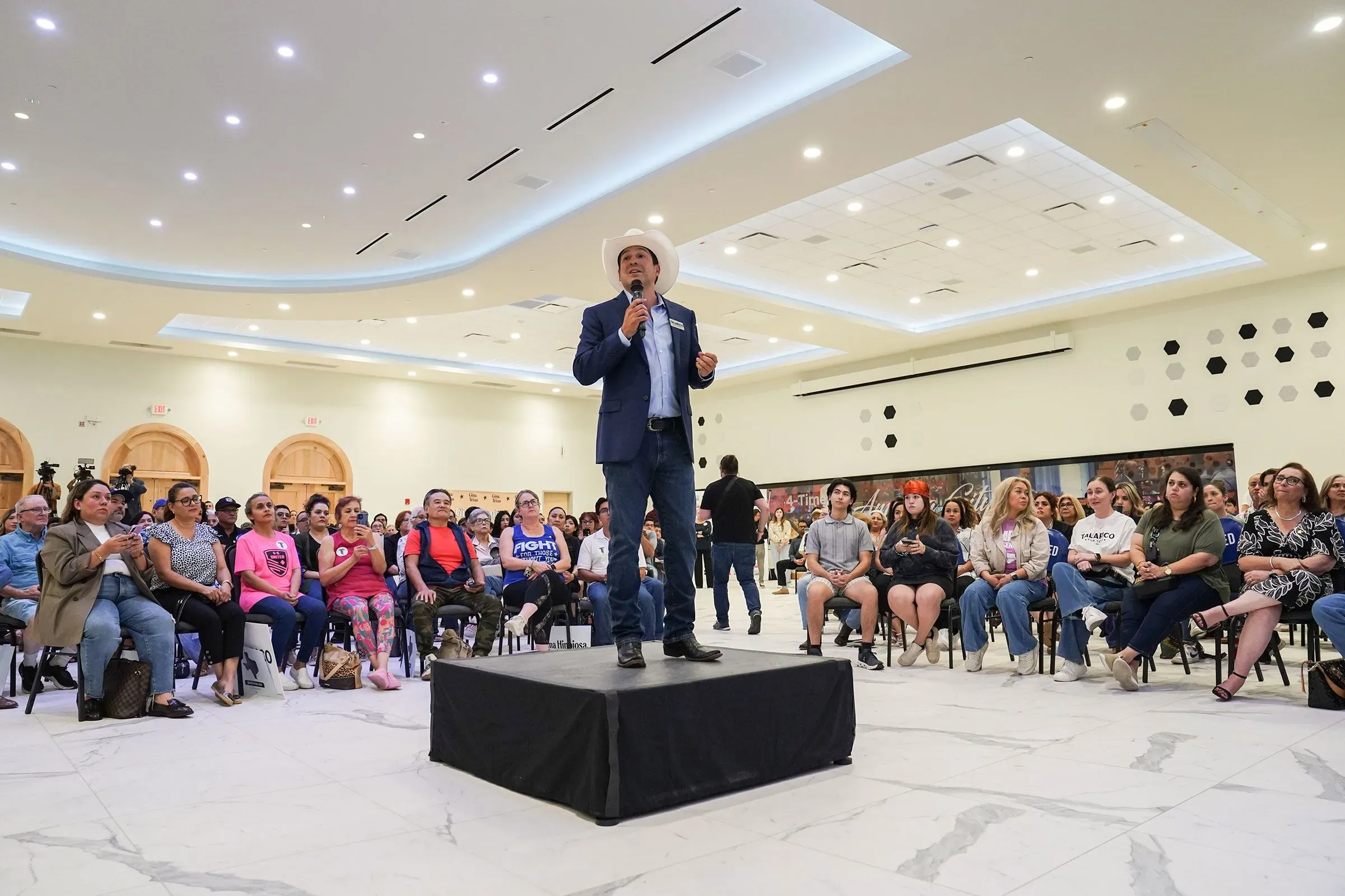 جيمي أجير يتحدث في تجمع انتخابي في ولاية تكساس، محاطًا بجمهور متنوع، مع التركيز على بناء العلاقات المجتمعية.