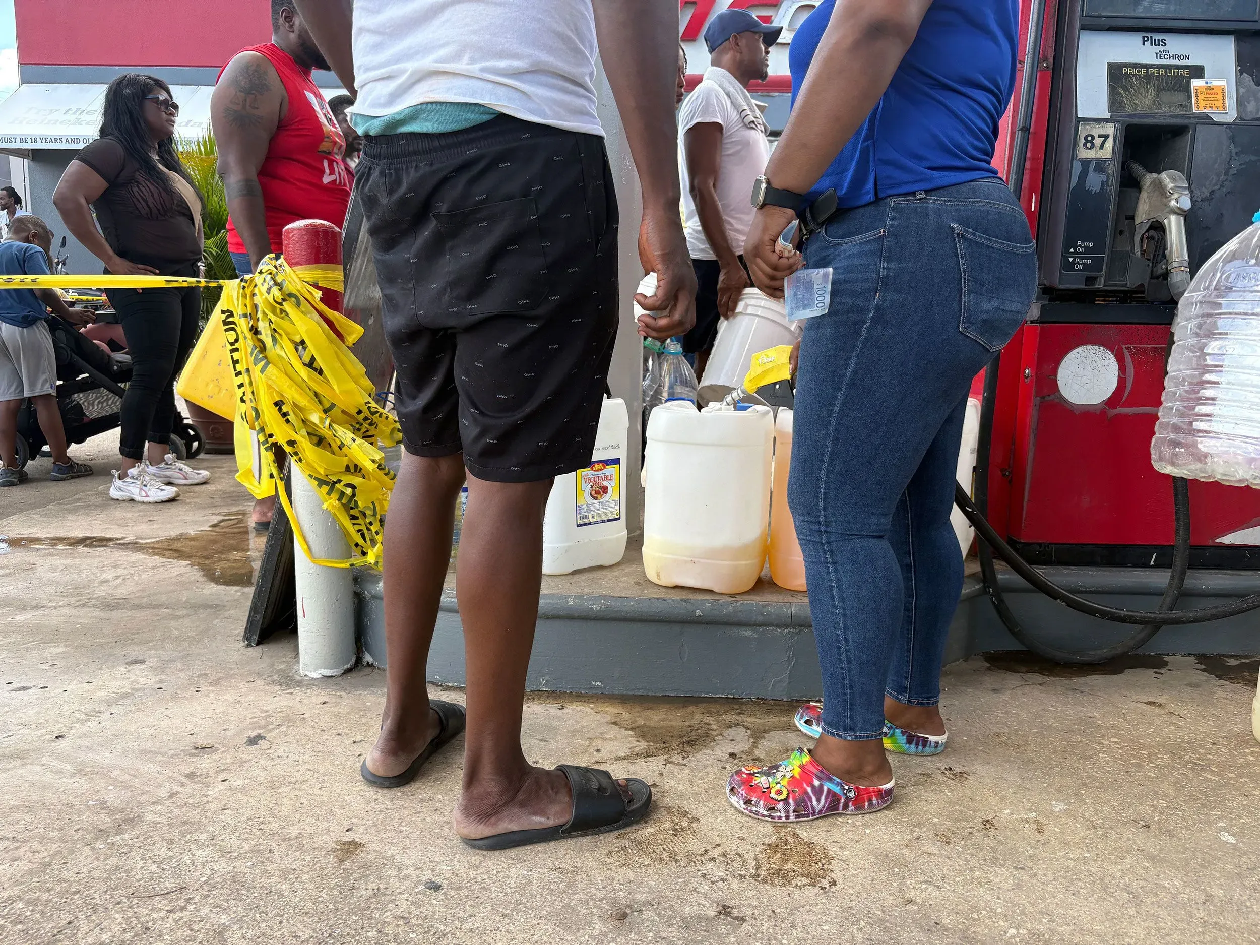 طوابير طويلة من الناس في محطة وقود في جامايكا، يسعون للحصول على الوقود بعد إعصار ميليسا. تظهر زجاجات مملوءة بالسوائل.