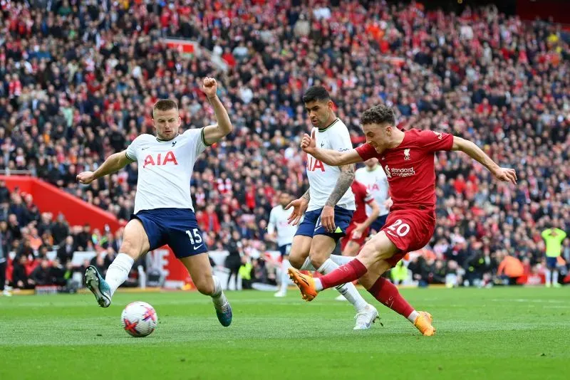 دييغو جوتا، لاعب ليفربول، يتحدى مدافعي توتنهام في مباراة حماسية، مع حشد من الجماهير في ملعب أنفيلد.