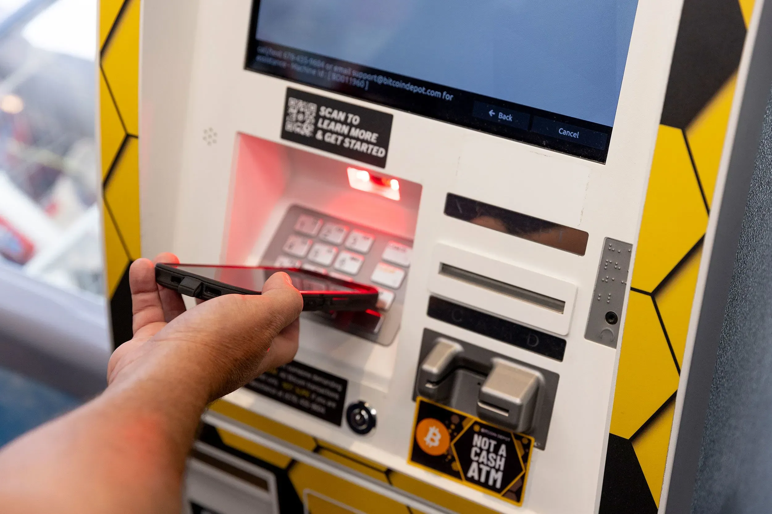 جهاز صراف آلي للعملات الرقمية يُستخدم لتحويل الأموال النقدية إلى عملة مشفرة، ويظهر شخص يستخدمه في عملية مشبوهة.