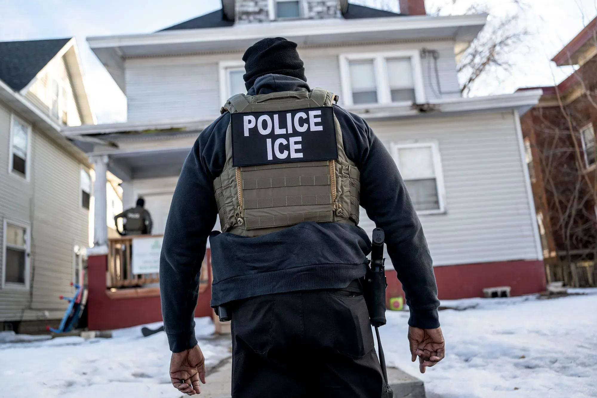 ضابط من إدارة الهجرة والجمارك (ICE) يتجه نحو منزل أثناء تنفيذ عمليات الترحيل، في سياق أزمة الهجرة الأوكرانية.