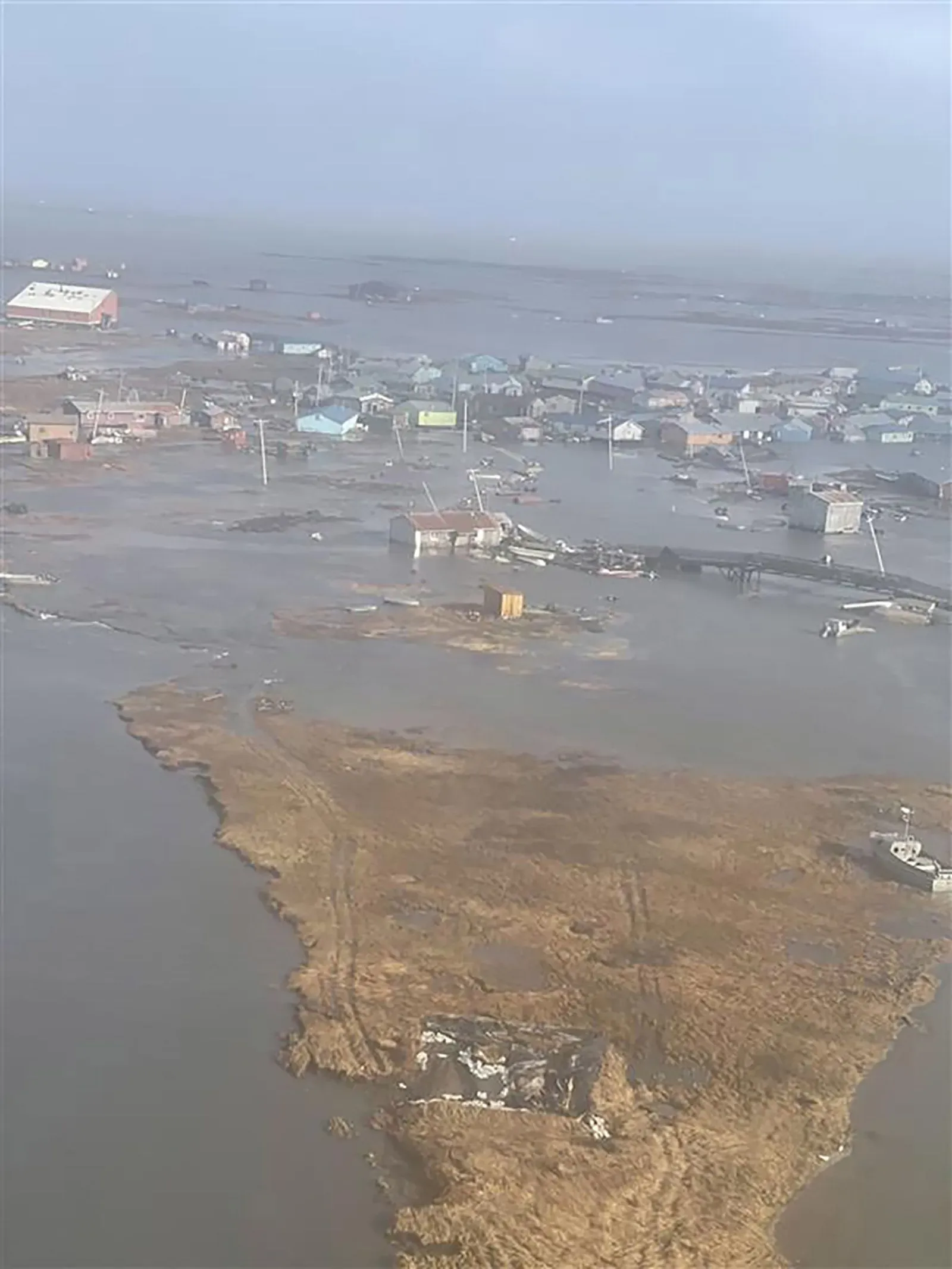 تظهر الصورة مشاهد للفيضانات في كويجيلينجوك، ألاسكا، مع منازل مدمرة ومياه مرتفعة بعد إعصار هالونج، مما يعكس الأضرار الجسيمة التي خلفتها العاصفة.