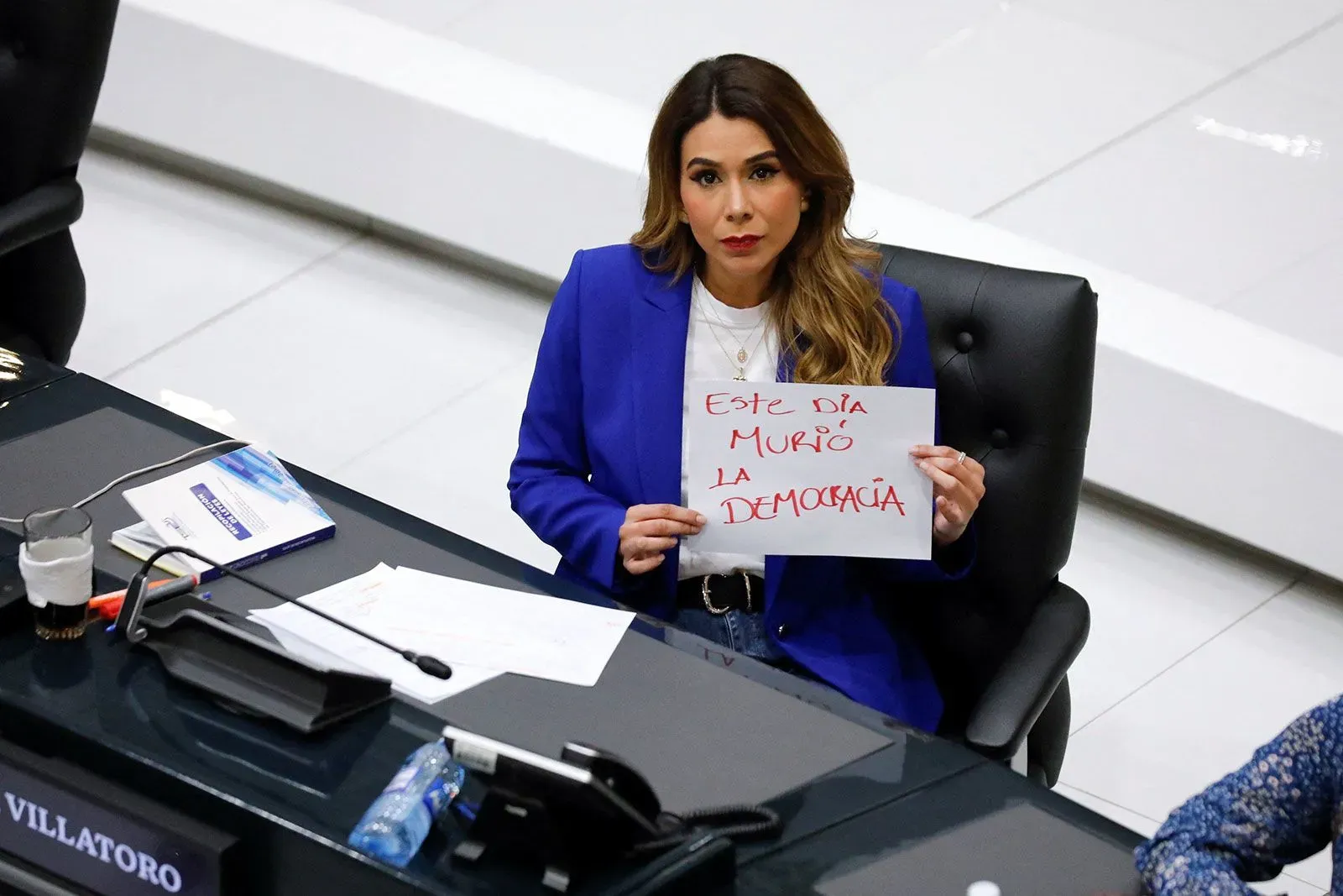 نائبة تحمل لافتة مكتوب عليها "هذا اليوم ماتت الديمقراطية" خلال جلسة تشريعية في السلفادور، تعبر عن قلقها بشأن التعديلات الدستورية.