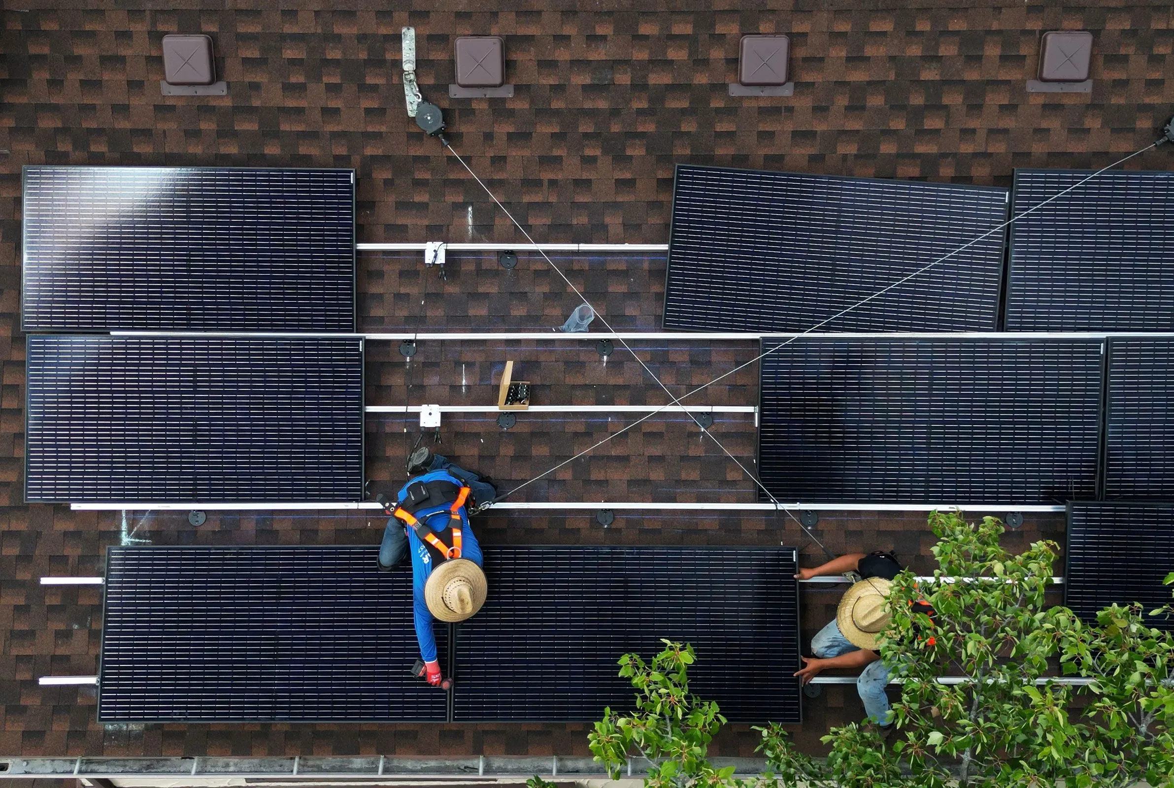 عمال يقومون بتركيب الألواح الشمسية على سطح منزل، مما يعكس الاتجاه المتزايد نحو استخدام الطاقة المتجددة في الولايات المتحدة.