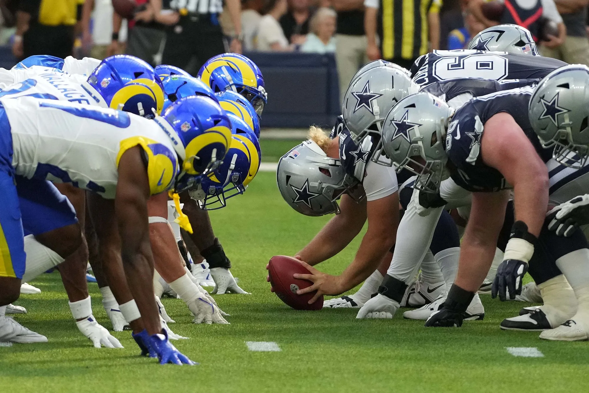 مواجهة بين لاعبي كرة القدم الأمريكية لفريقي Dallas Cowboys وLos Angeles Rams، تعكس المنافسة الشديدة في عالم الرياضة.