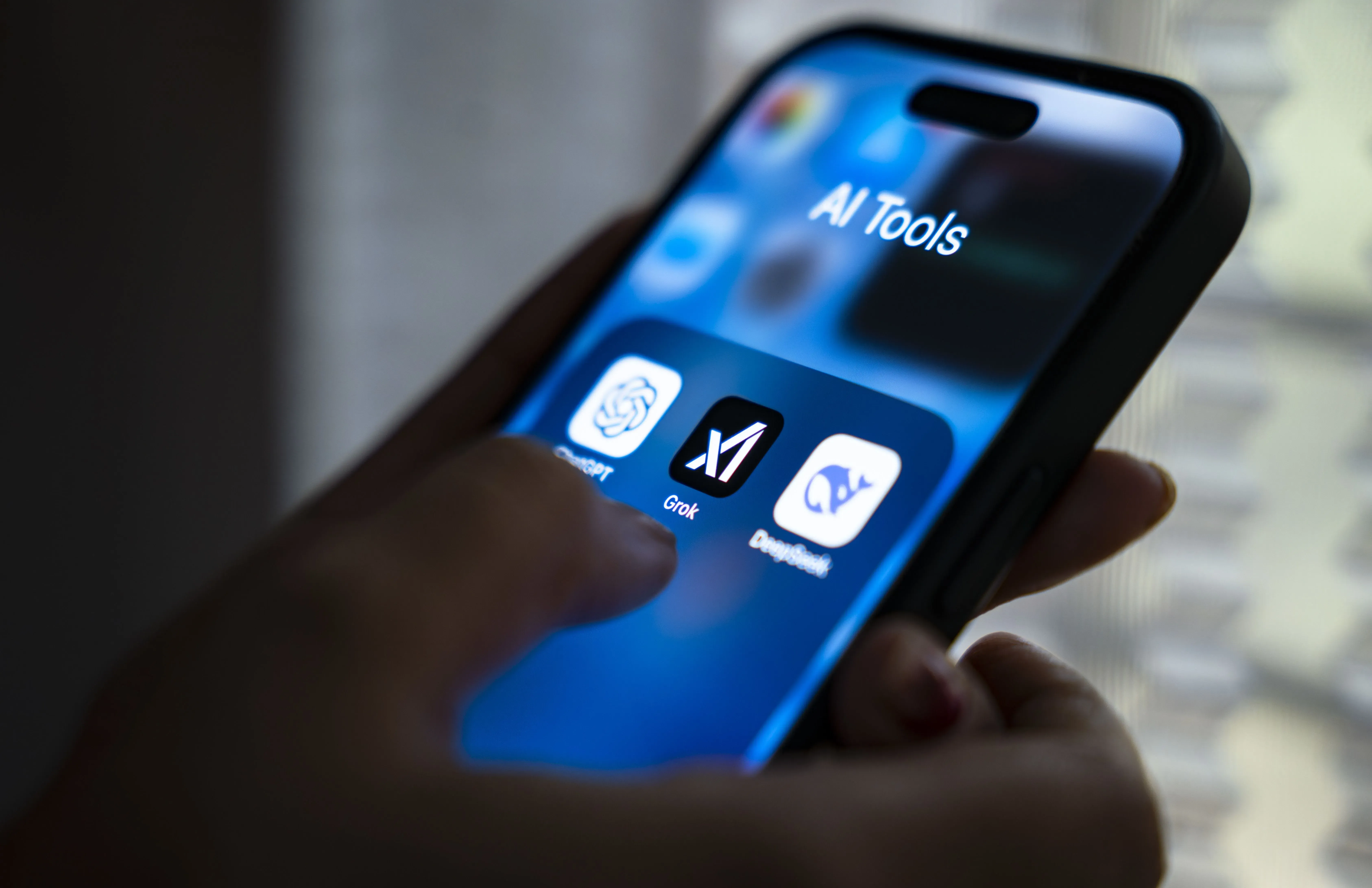واجهة تطبيقات الذكاء الاصطناعي على هاتف ذكي تظهر أيقونات ChatGPT وGrok وDeepMind، مع يد تلمس الشاشة.