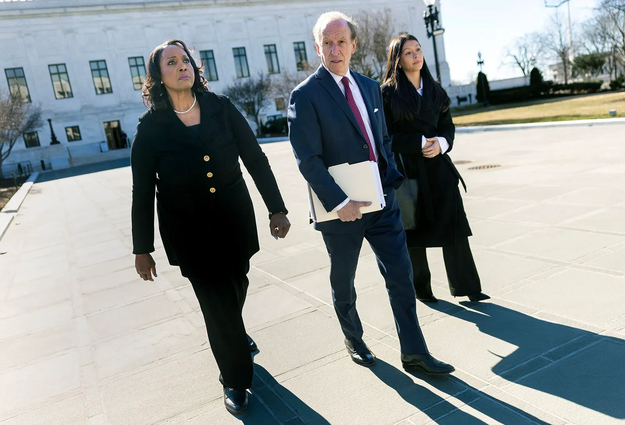 مجموعة من المسؤولين يسيرون نحو مبنى المحكمة العليا، حيث يناقشون قضايا تتعلق باستقلالية الاحتياطي الفيدرالي.