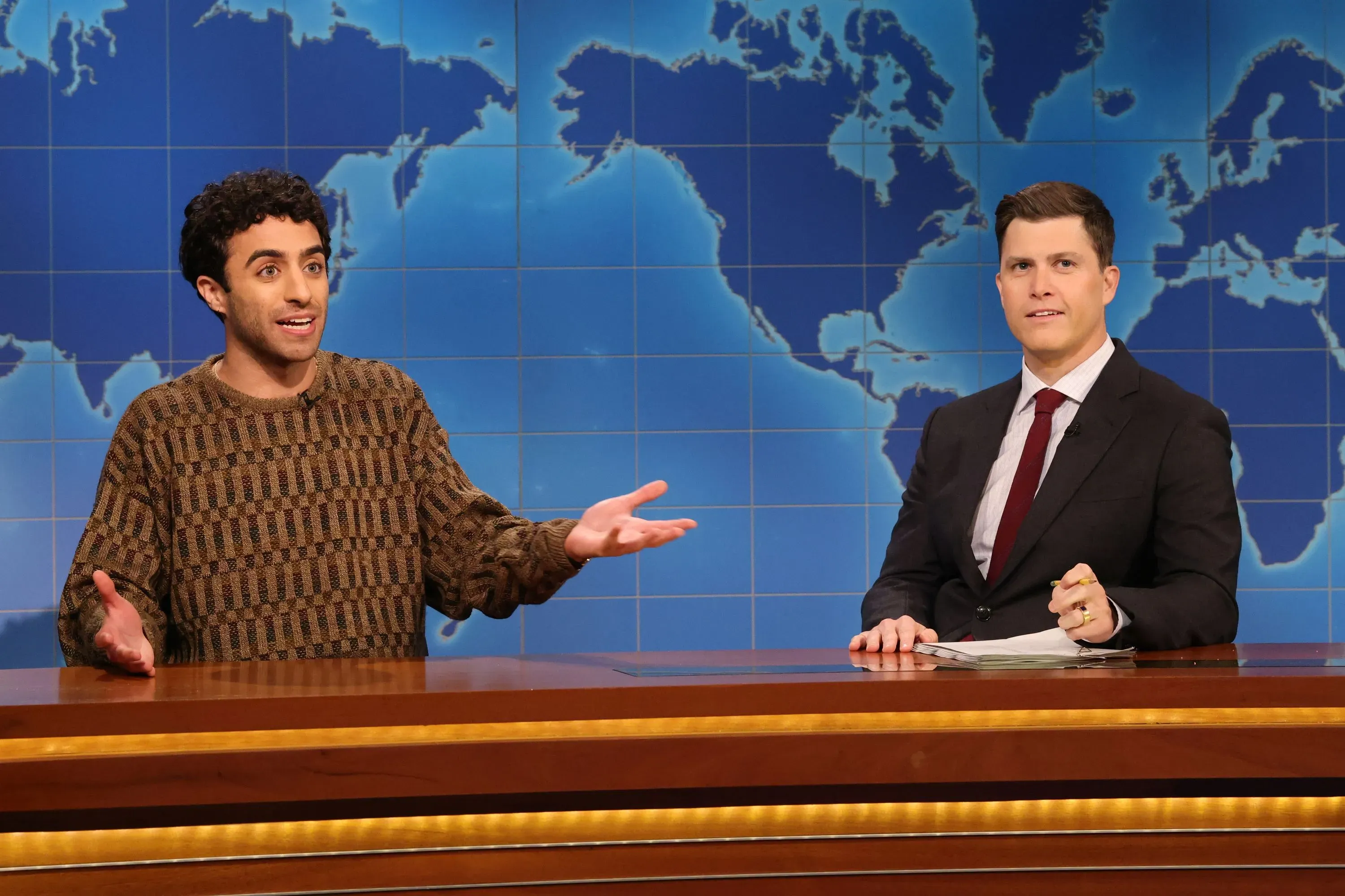 إميل واكيم يتحدث على منصة برنامج "ساترداي نايت لايف" مع خلفية خريطة العالم، معبراً عن مشاعره حول مغادرته للبرنامج.