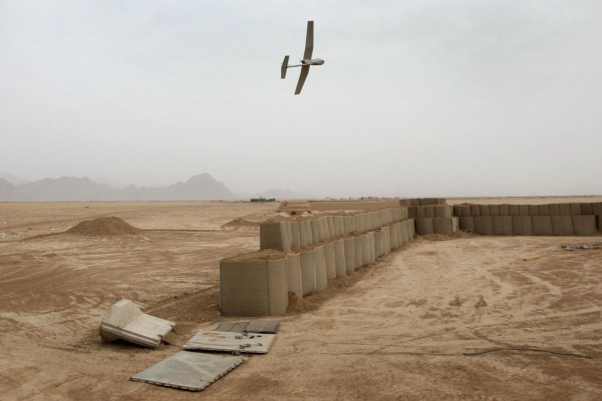 طائرة مسيرة تحلق فوق منطقة صحراوية، تُظهر الجدران الخرسانية المحيطة، في سياق العمليات العسكرية ضد تهريب المخدرات.