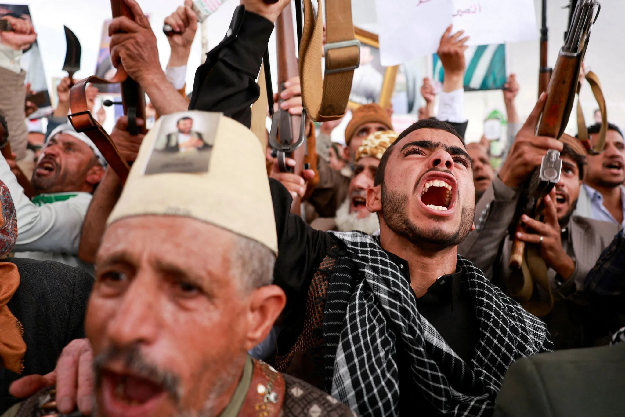 مسلحون حوثيون يرفعون أسلحتهم ويهتفون في تجمع يعكس تصعيد النزاع في اليمن وتأثيره على الأمن الإقليمي ومضيق باب المندب.