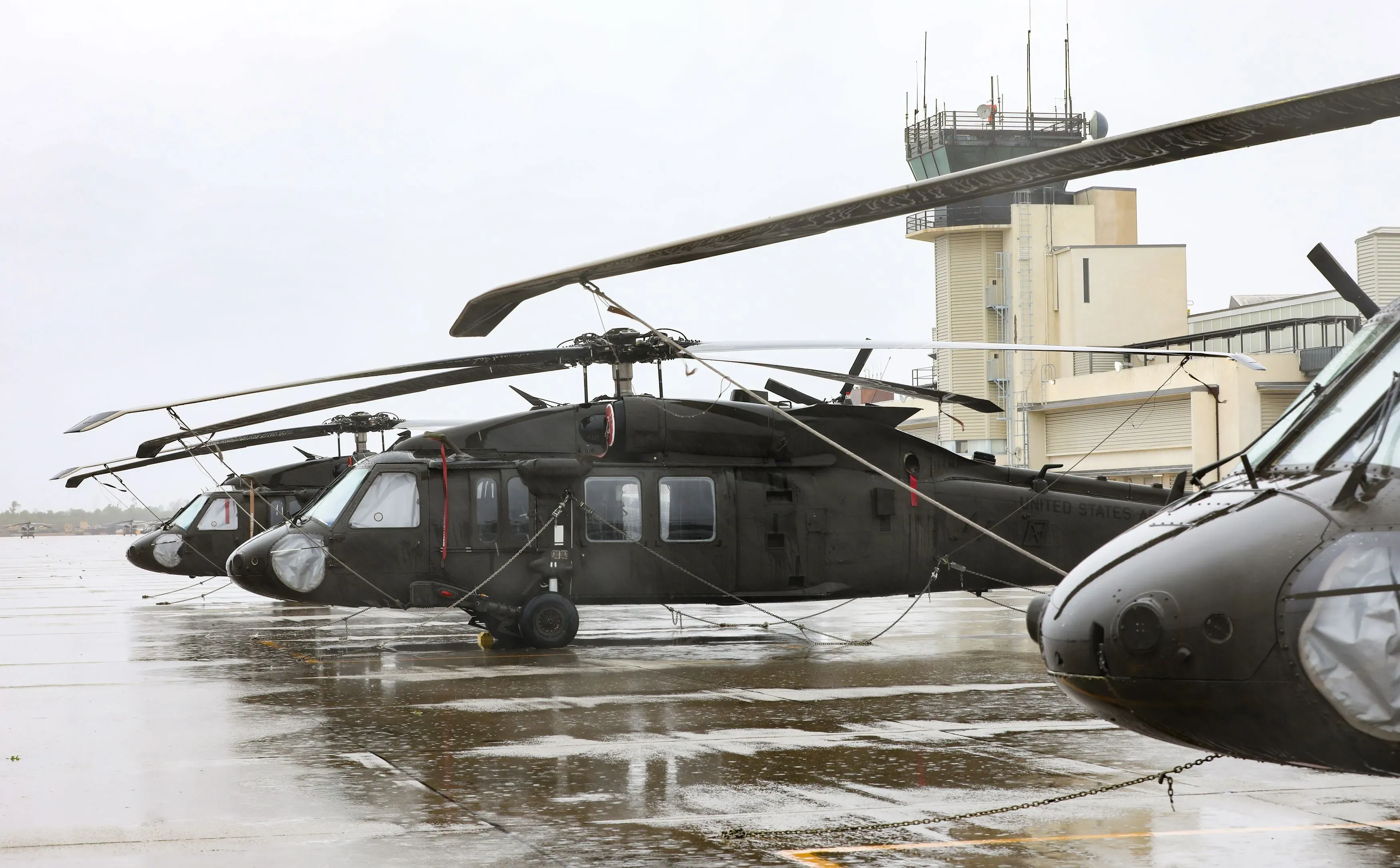 مروحية بلاك هوك تابعة للحرس الوطني الأمريكي متوقفة في مطار، مع برج مراقبة خلفها، في سياق تحقيق حول حادث قرب مطار جون واين.