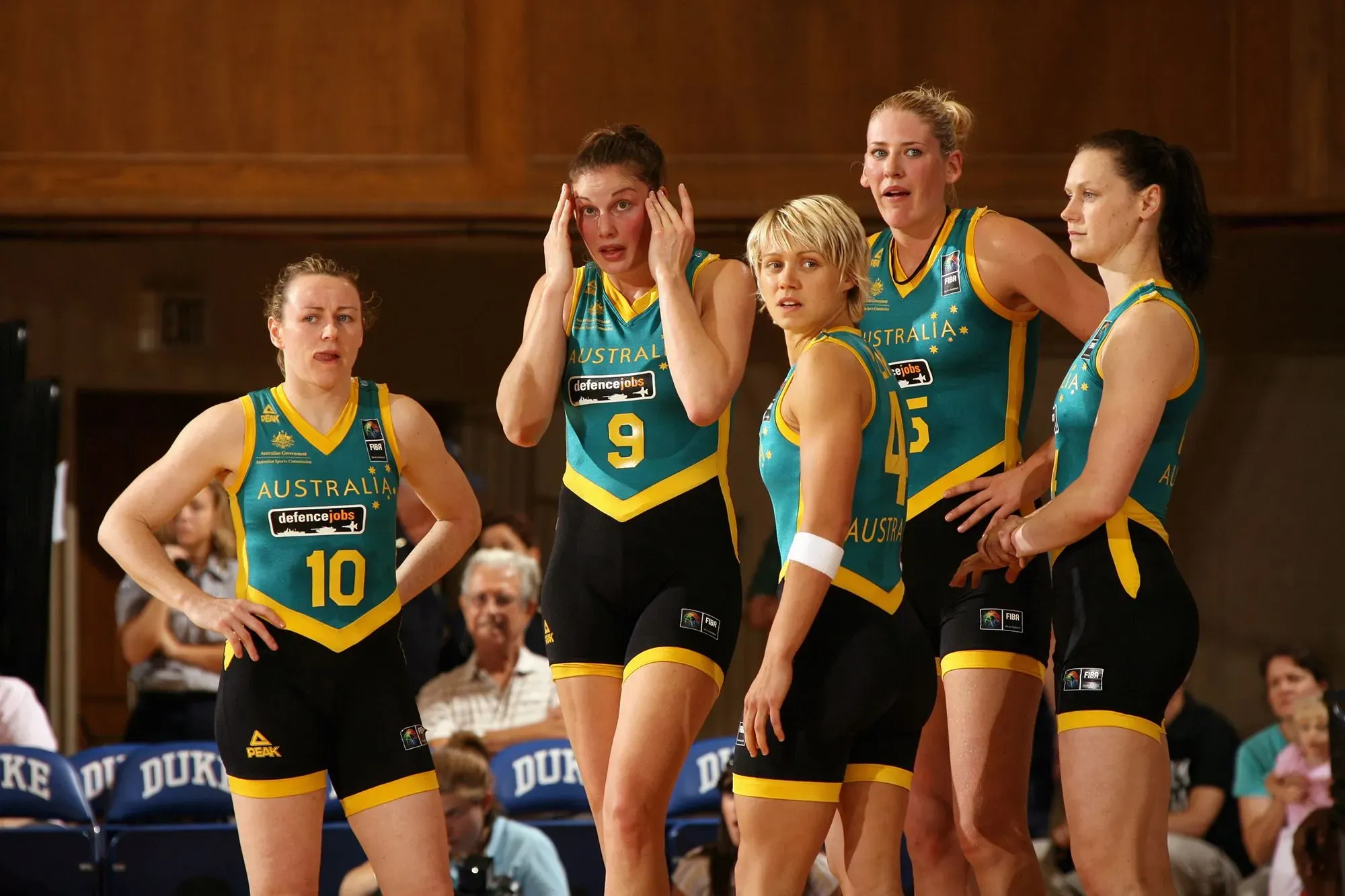 لاعبات كرة السلة الأستراليات يرتدين زيًا ضيقًا أثناء مباراة، مع تعبيرات وجه تعكس الإحراج والقلق بشأن الزي الرسمي.