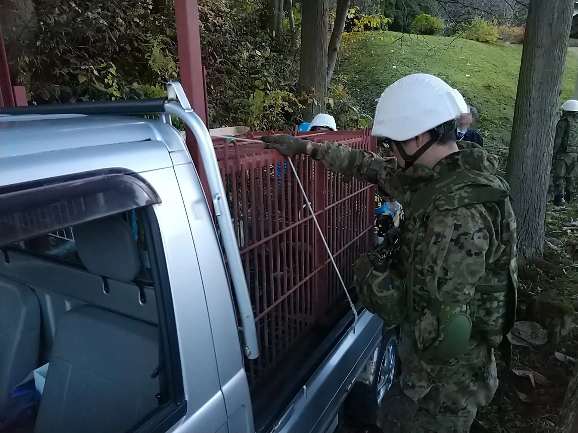 جنود يابانيون يرتدون خوذات واقية يتفقدون صندوقًا في شاحنة صغيرة، استعدادًا لمواجهة هجمات الدببة في محافظة أكيتا.