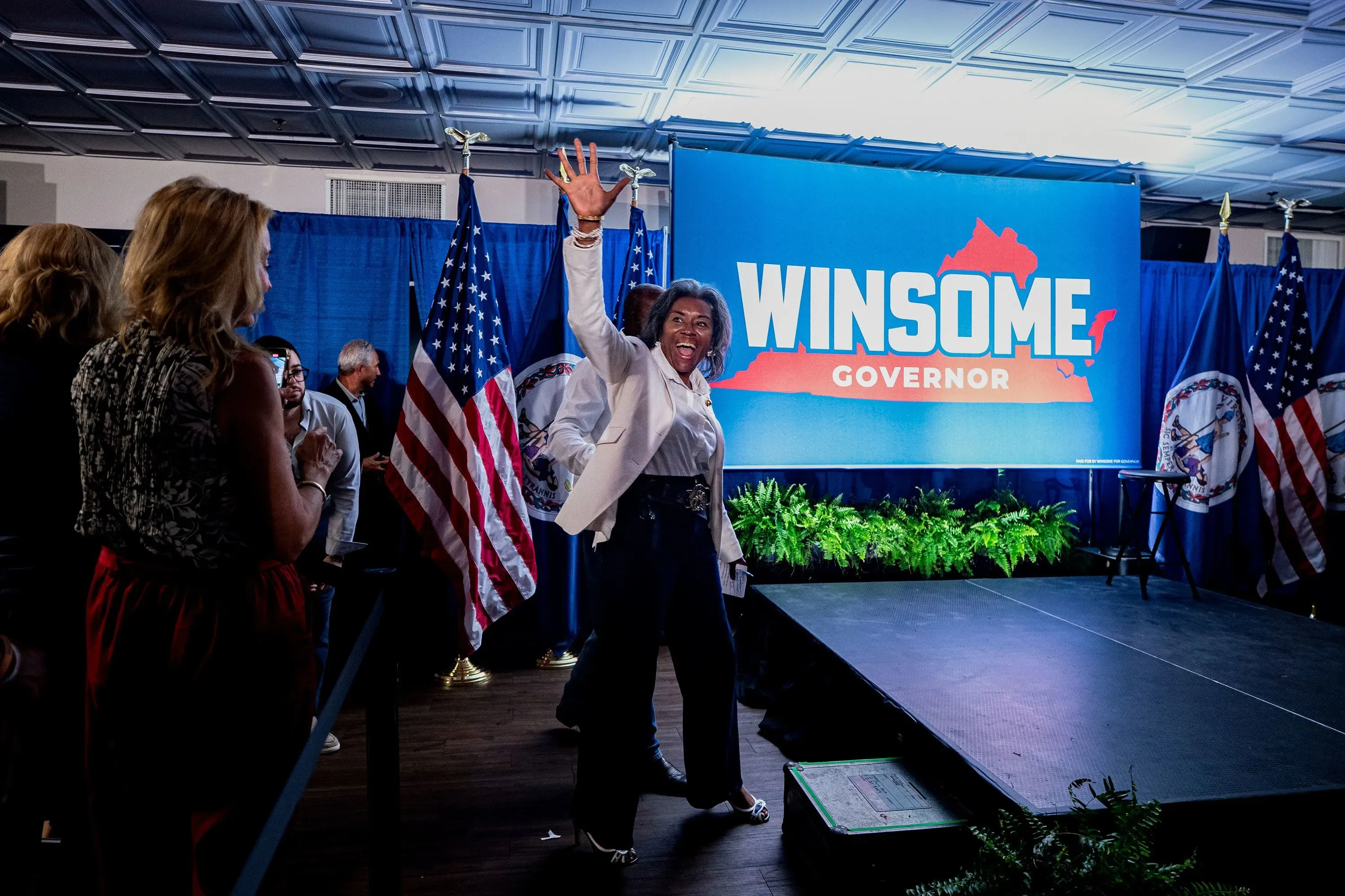 وينسوم إيرل-سيرز تتحدث بحماس أمام حشد من المؤيدين في مطعم فلبيني بفيرجينيا، مع خلفية تحمل شعار "حاكمة".