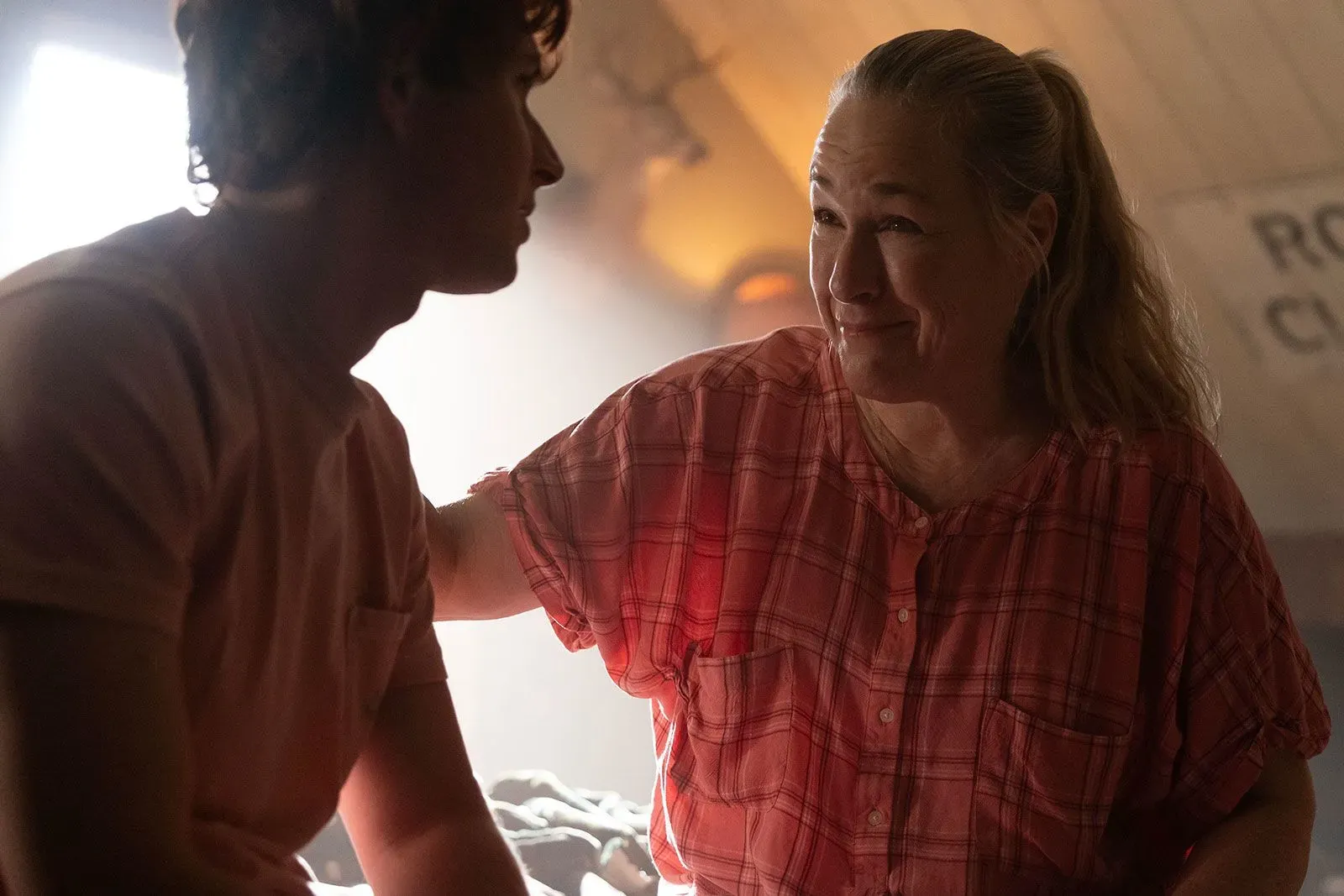 مشهد درامي يظهر امرأة في قميص مخطط، تتحدث مع شاب بملامح عاطفية، في سياق مسلسل يتناول قضايا عائلية معقدة.