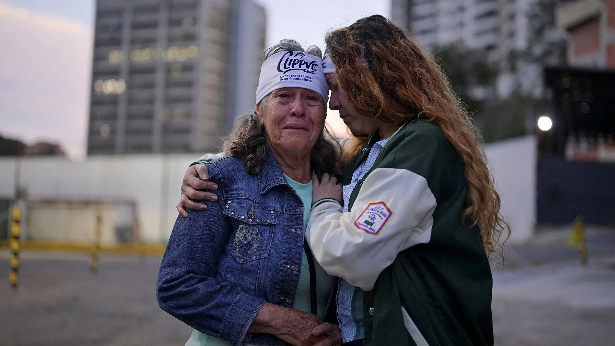 امرأة مسنّة تبكي بينما تحتضن ابنتها، تعبيرات وجههما تعكس القلق والأمل في ظل الوضع السياسي الصعب في فنزويلا.