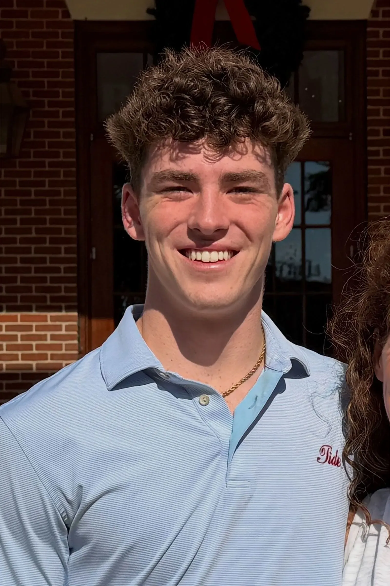 طالب جامعي أمريكي يُدعى جيمس غرايسي، مبتسم، يرتدي قميصًا أزرق وسلسلة ذهبية، في صورة تبرز ملامحه.